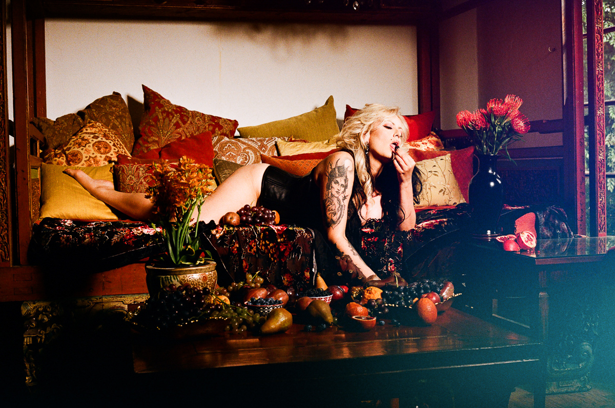 A woman laying on a couch next to a table full of fruit.