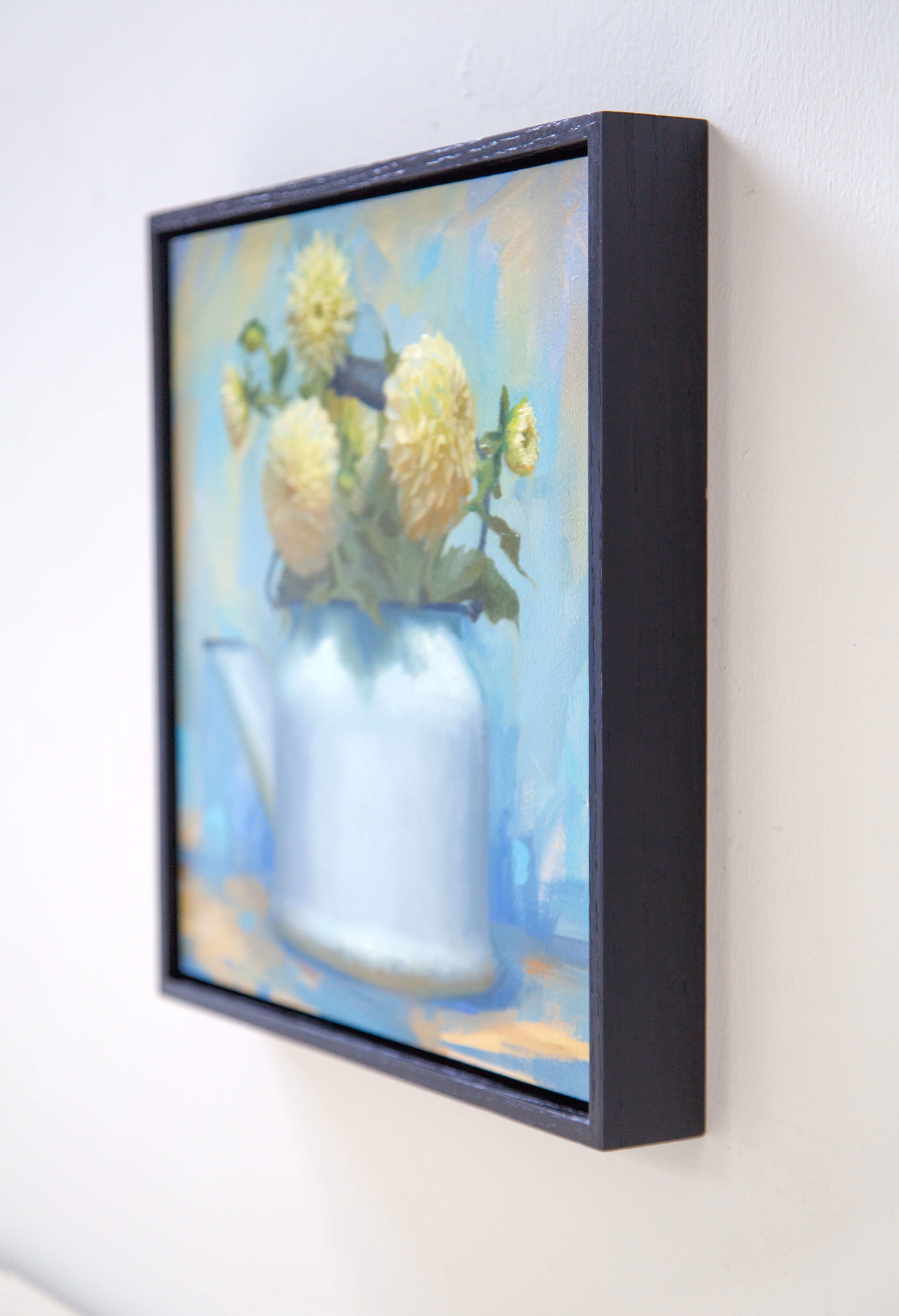 A still life painting of pale yellow flowers in a white watering can against a soft blue background.