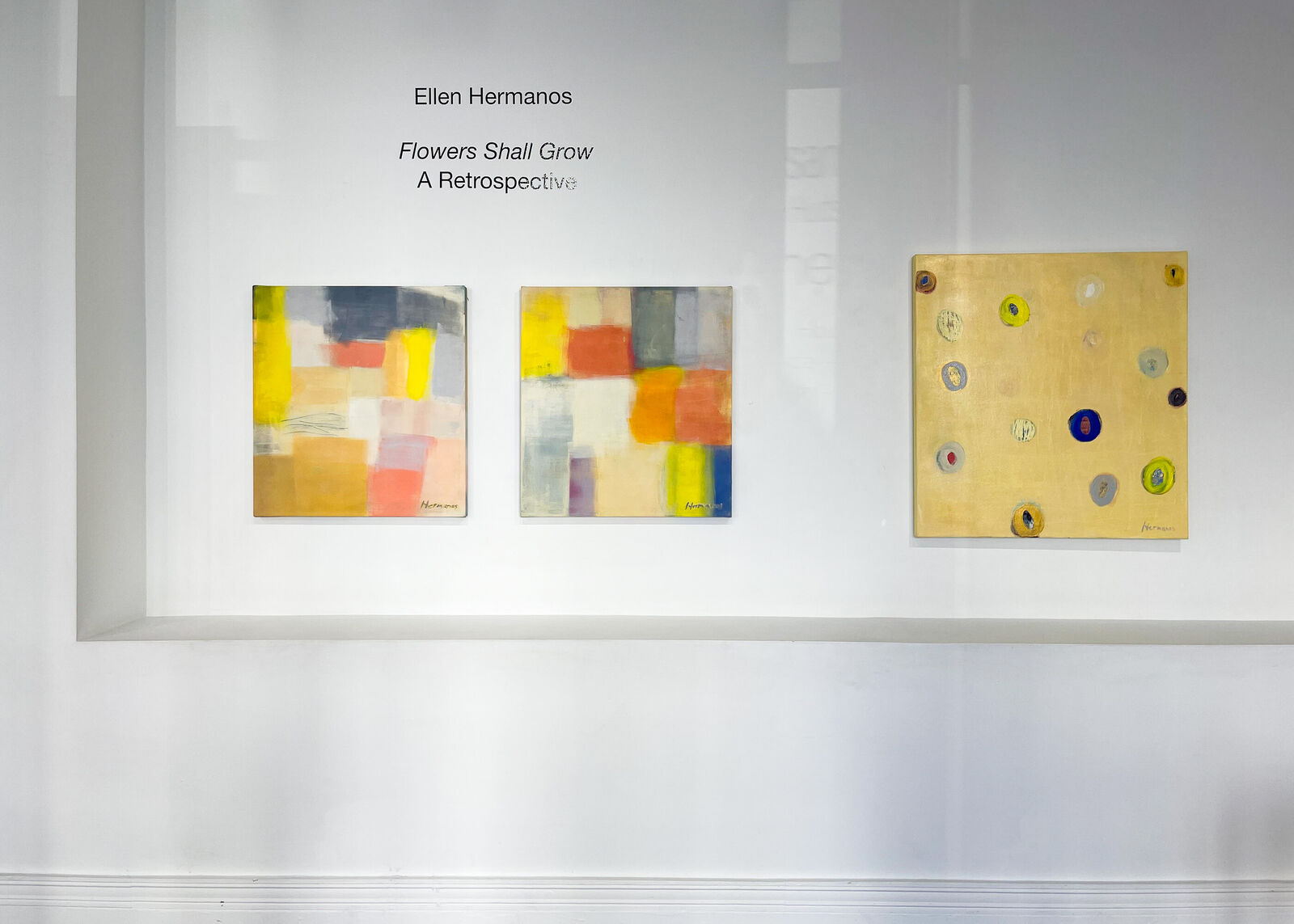 A vibrant abstract composition featuring scattered colorful circles on a textured golden-yellow canvas.