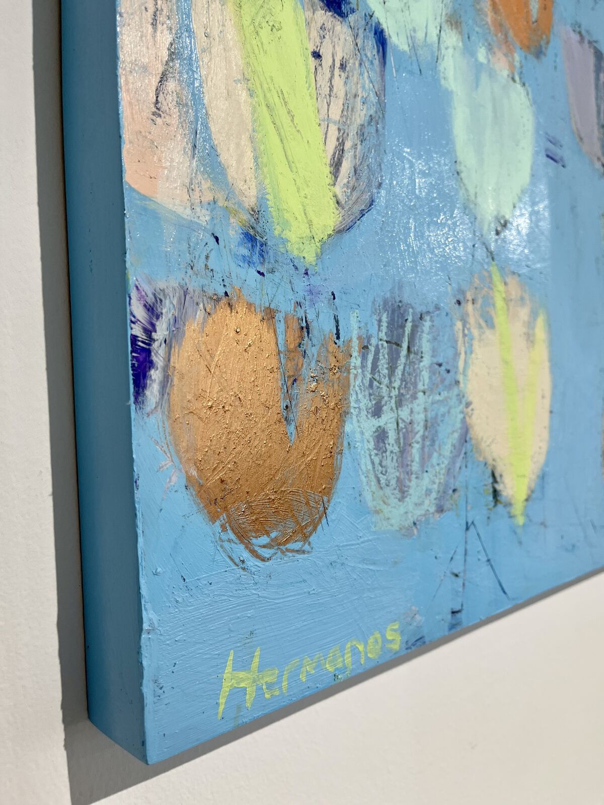 An abstract expressionist painting featuring a light blue background with scattered, colorful organic shapes.