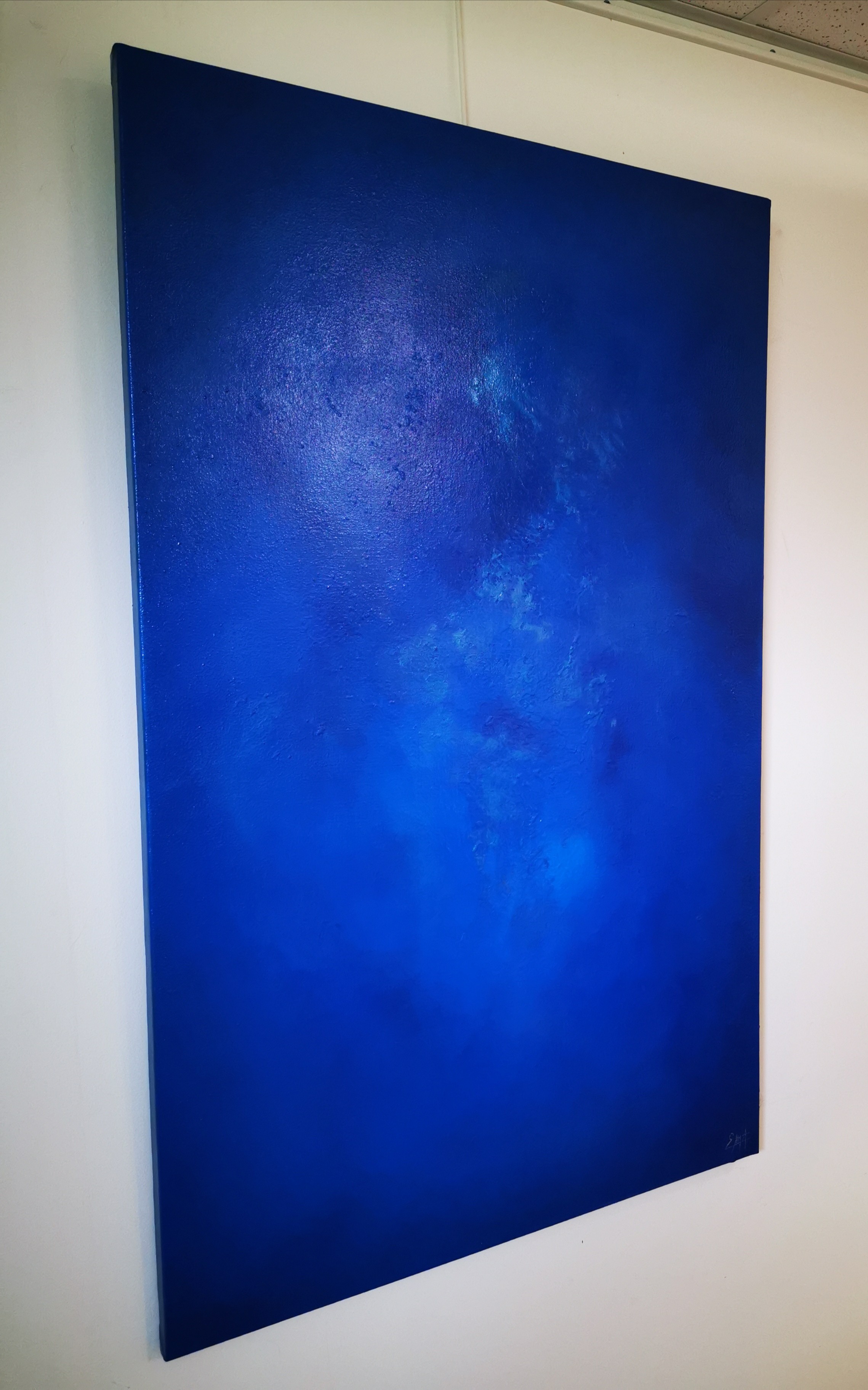A large blue painting hanging on a wall.