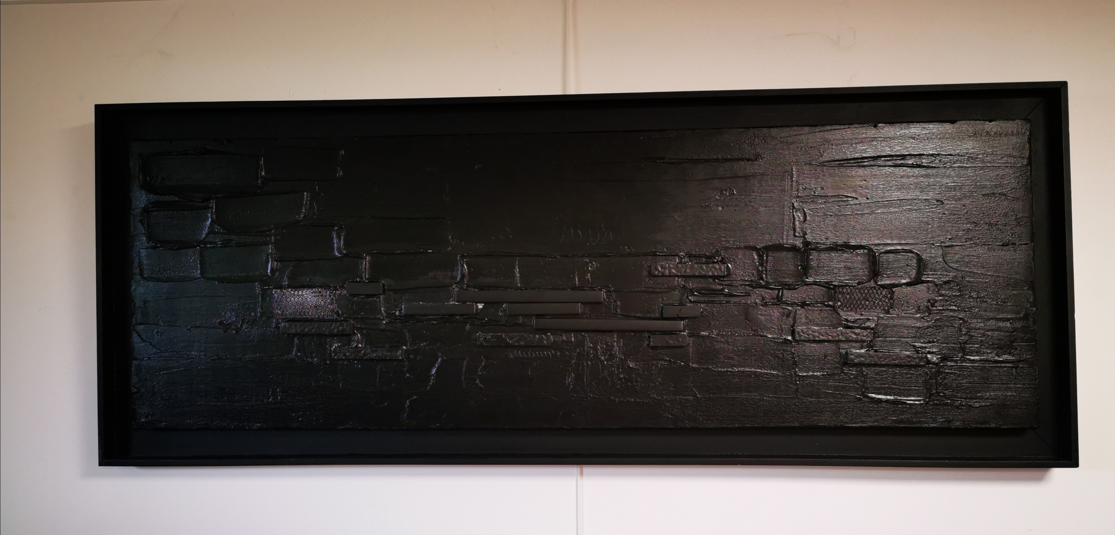 A black painting hanging on a wall in a room.