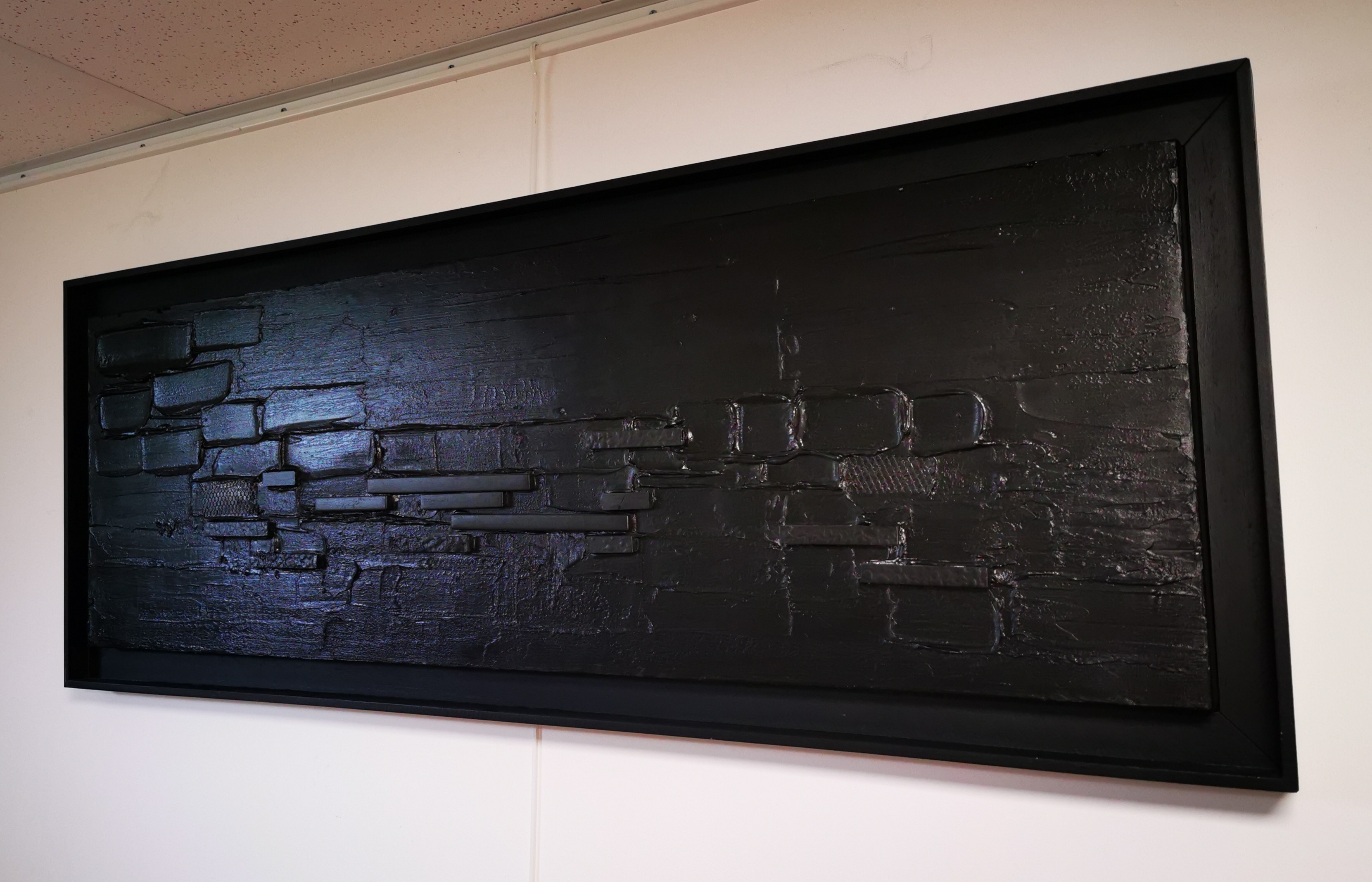 A black painting hanging on a wall in a room.