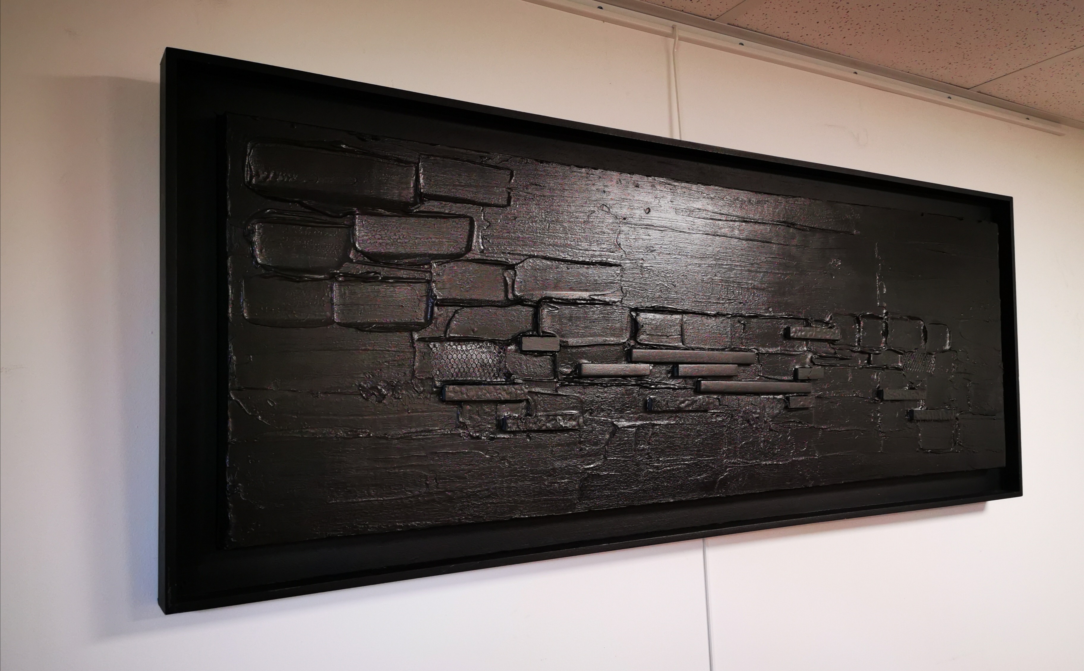 A black painting hanging on a wall in a room.