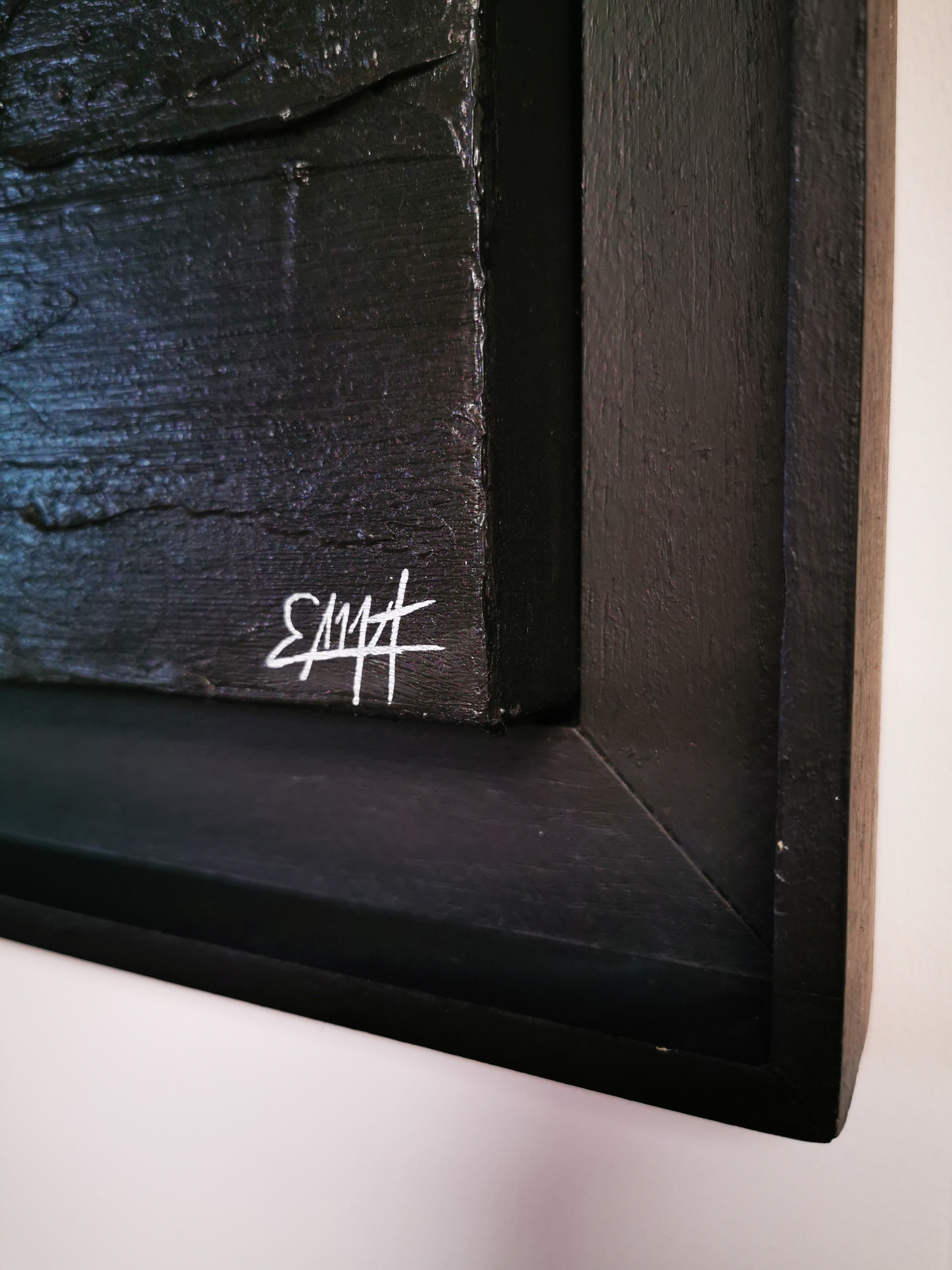 A black painting hanging on a wall in a room.