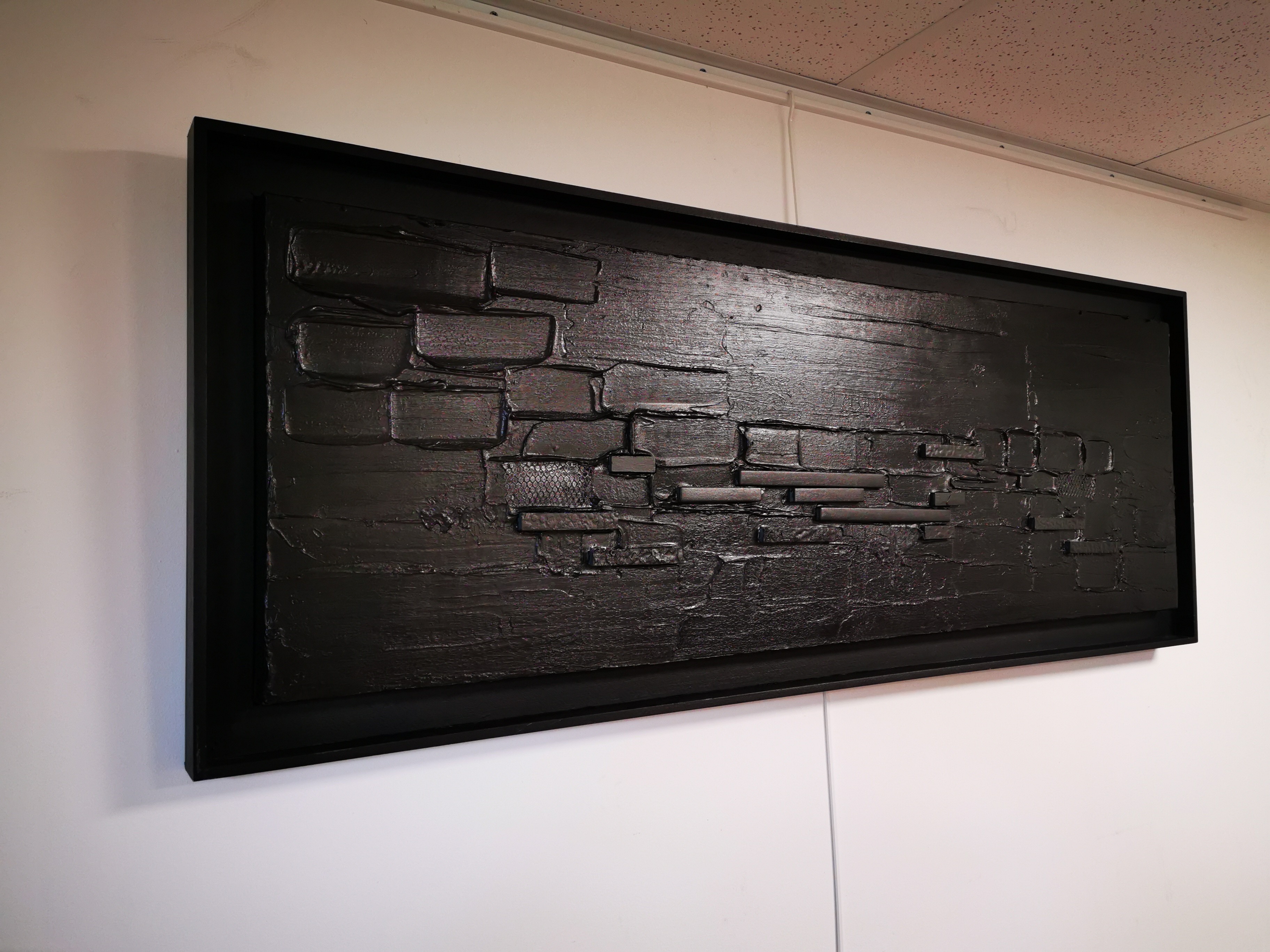 A black painting hanging on a wall in a room.