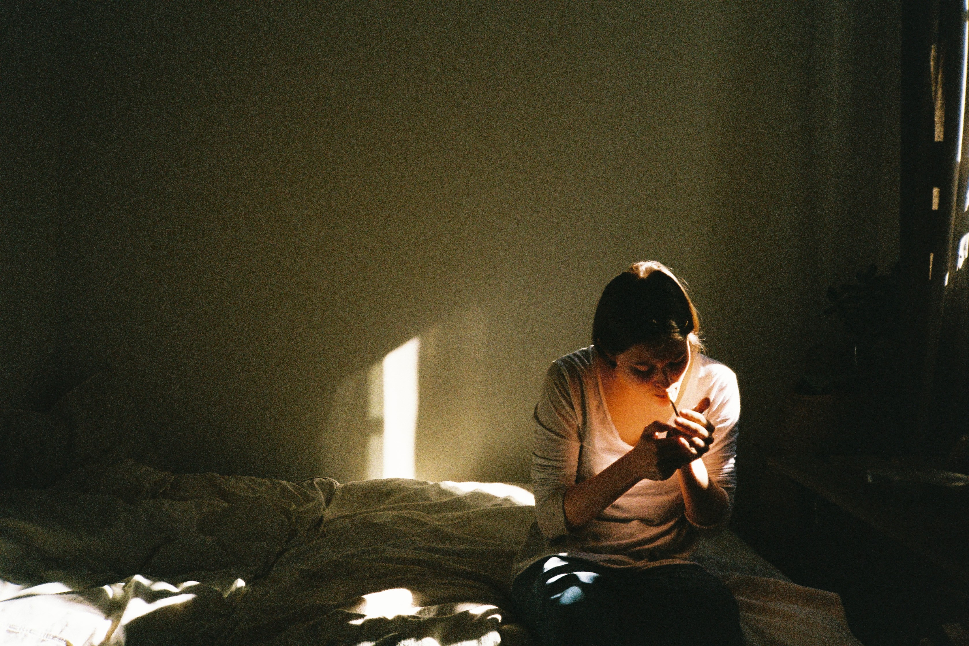 A woman sitting on a bed looking at her cell phone.