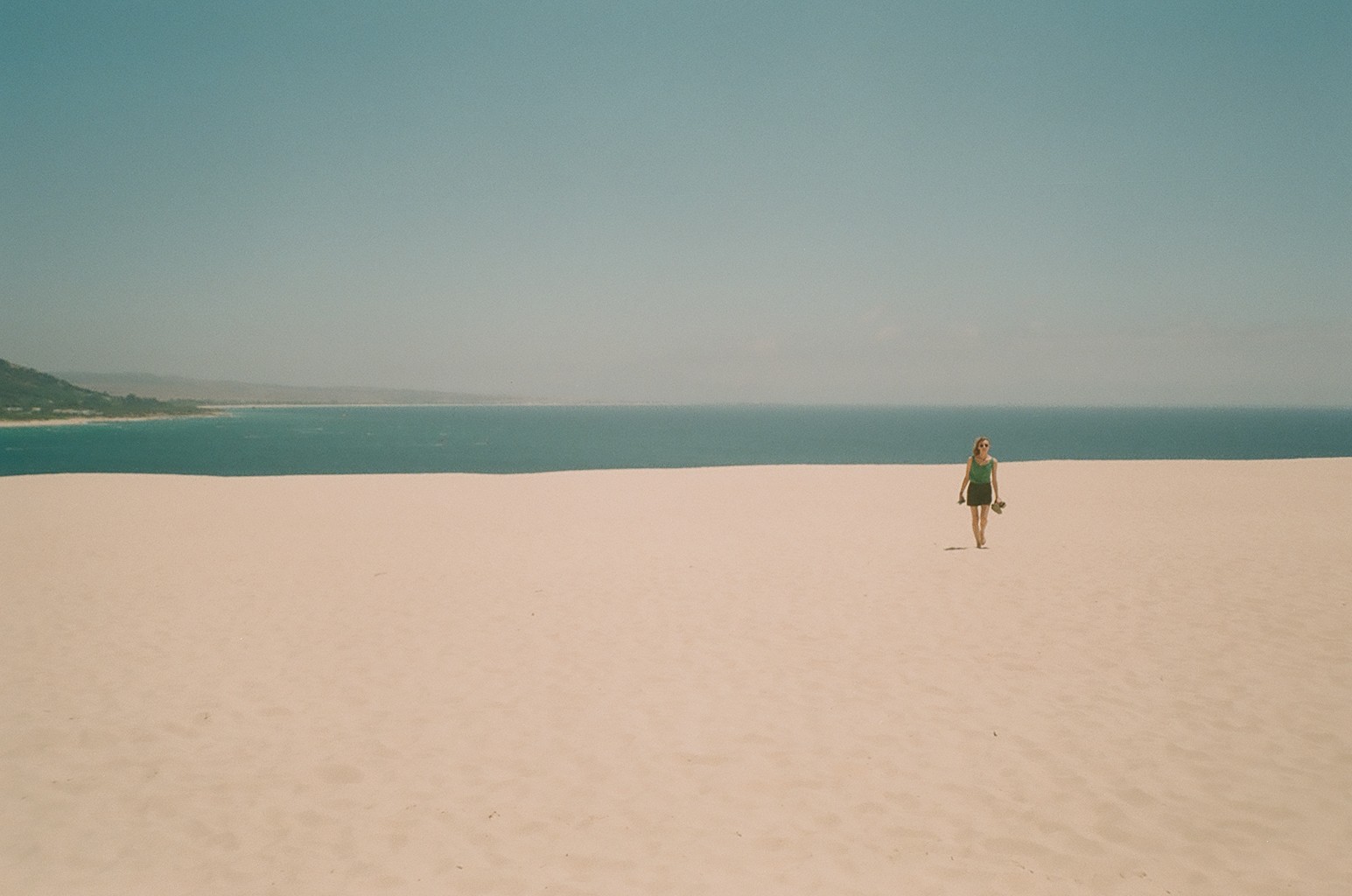 A woman walking across a sandy beach next to the ocean.