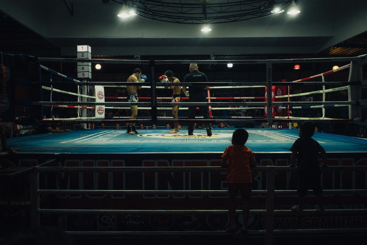 A group of people standing around a boxing ring.