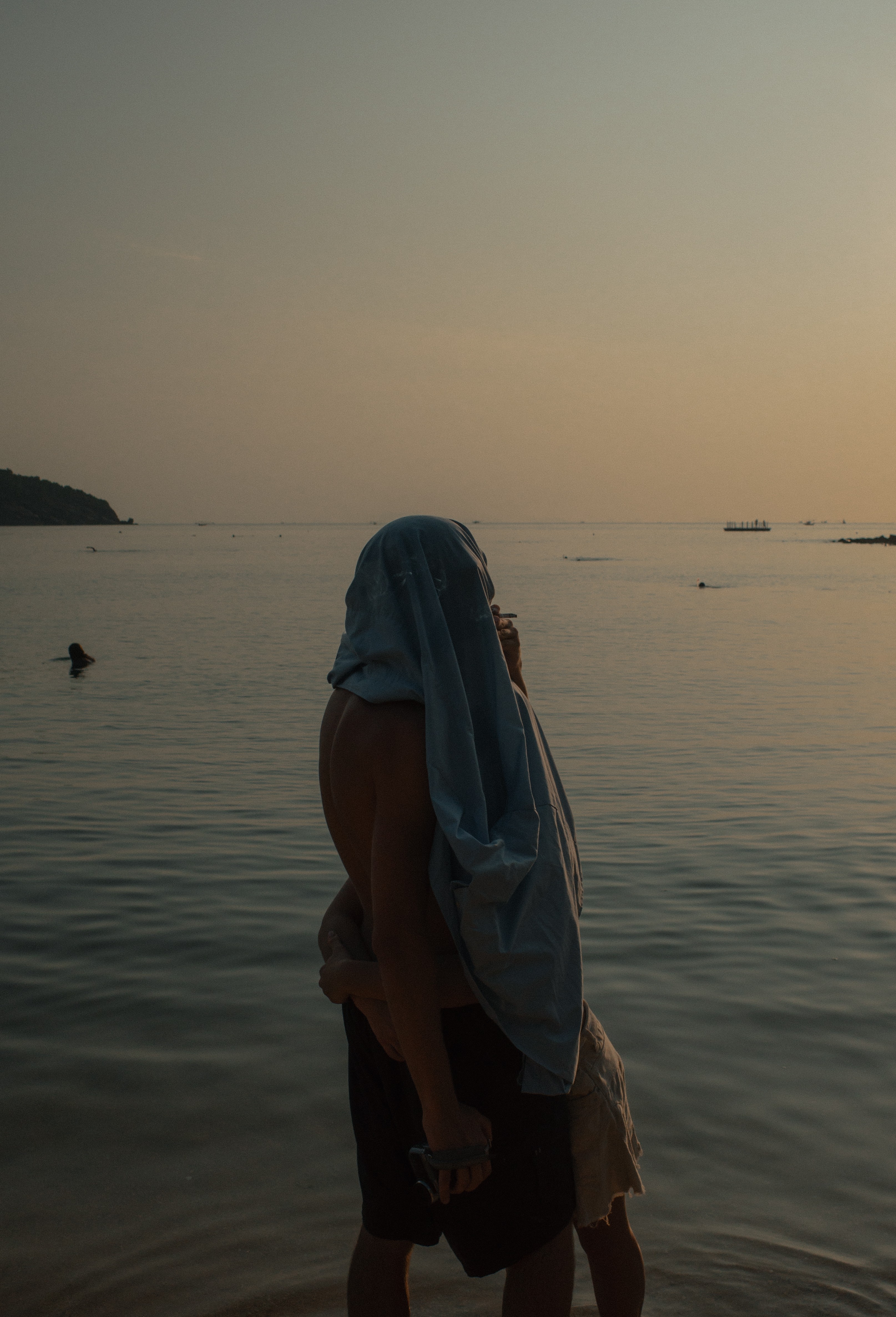 A man with a towel wrapped around his head standing in the water.