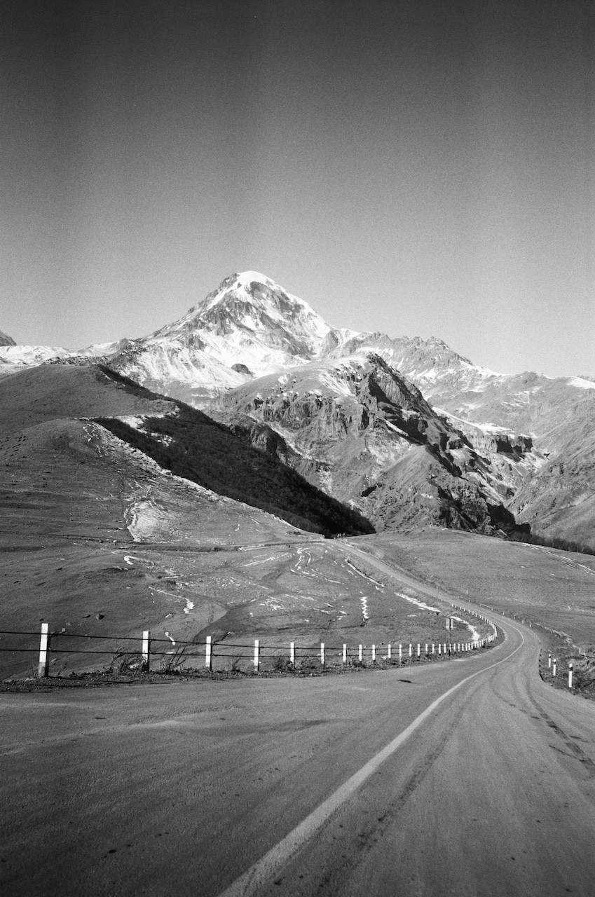 A black and white photo of a mountain road.