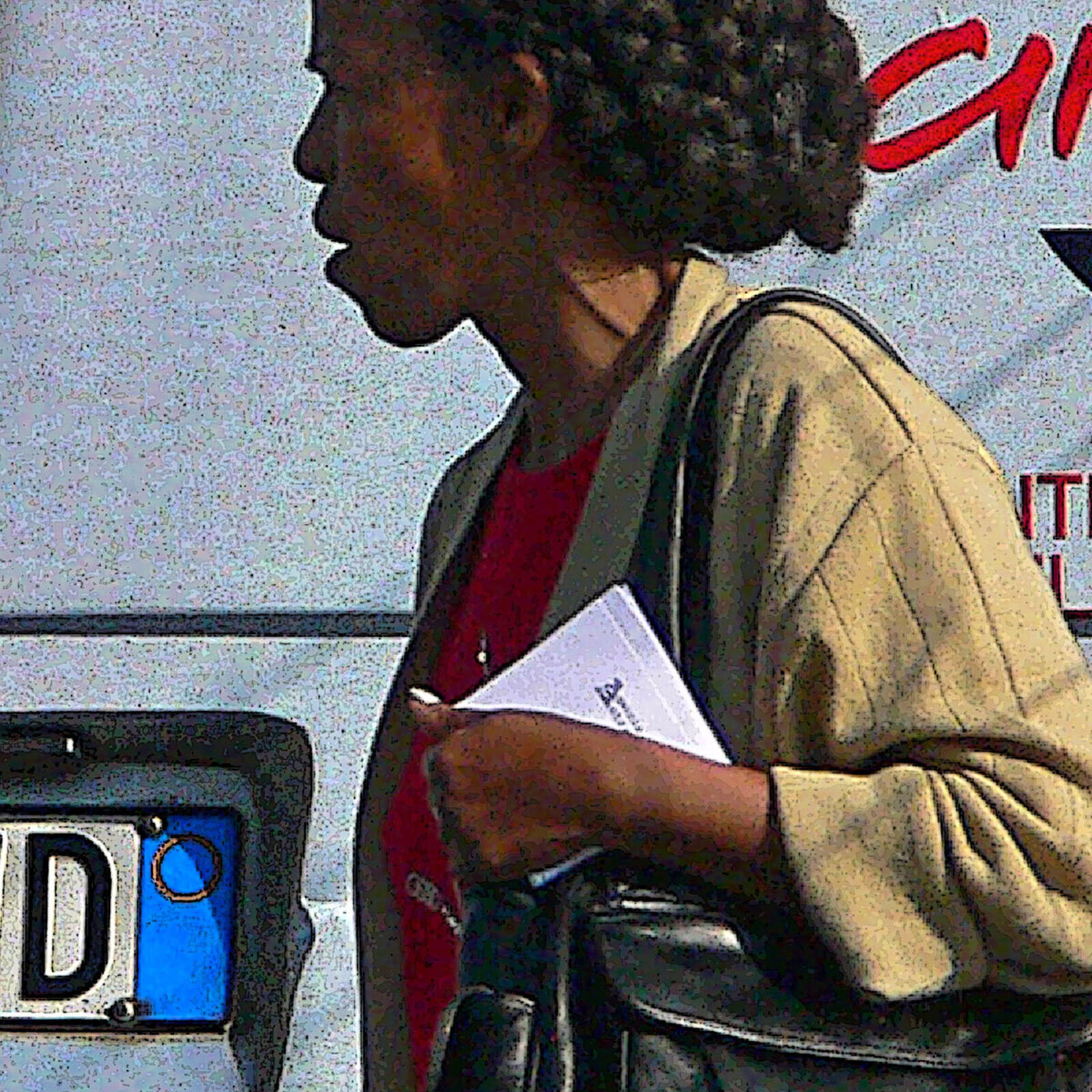 A woman walking past a bus with a poster on the back.