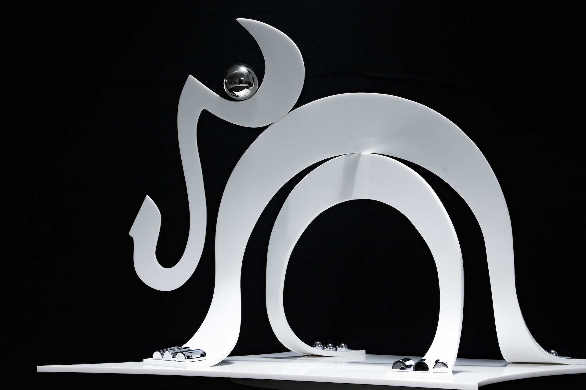 A white sculpture of a cat on a black background.