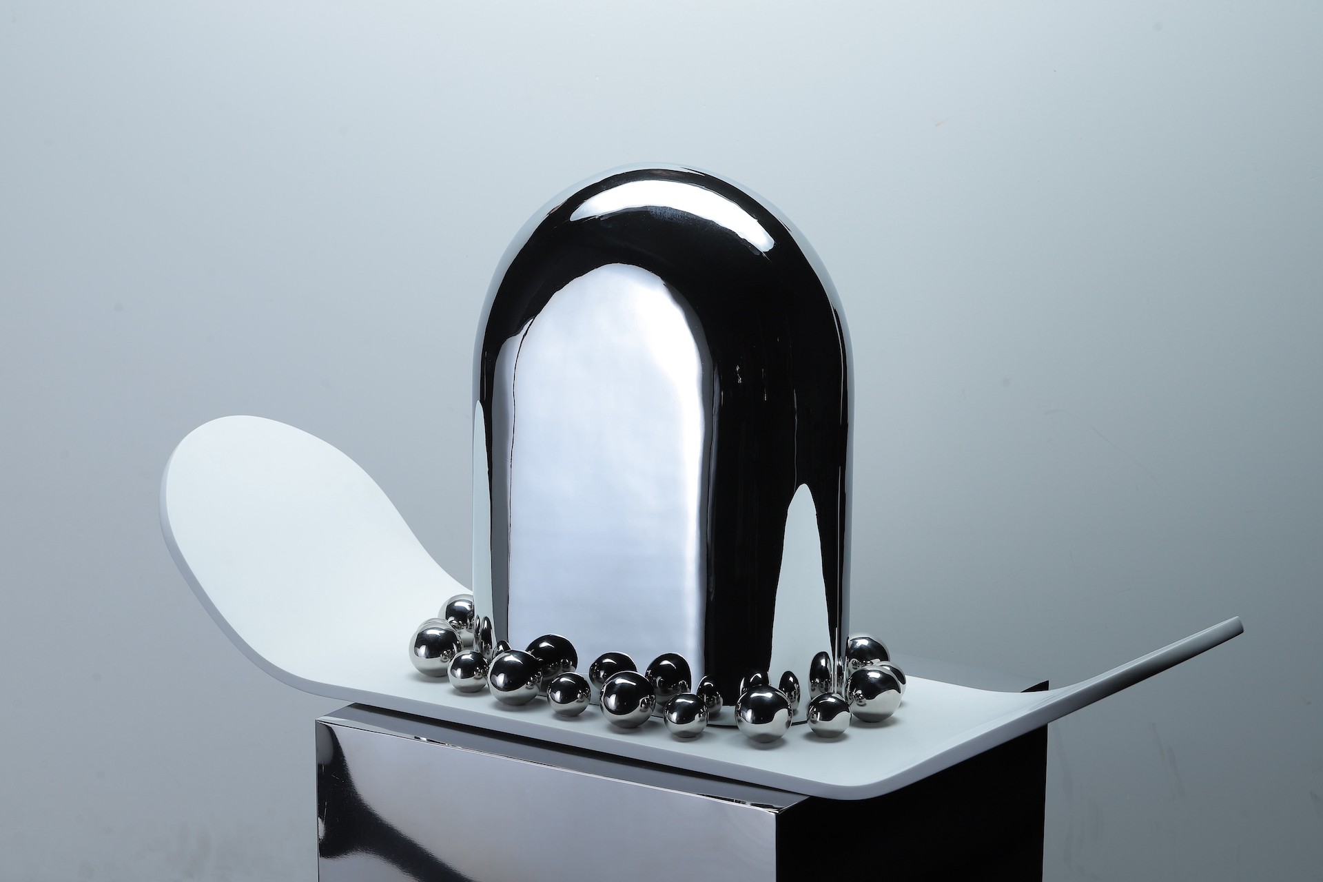 A black and white sculpture with silver balls on top of it.