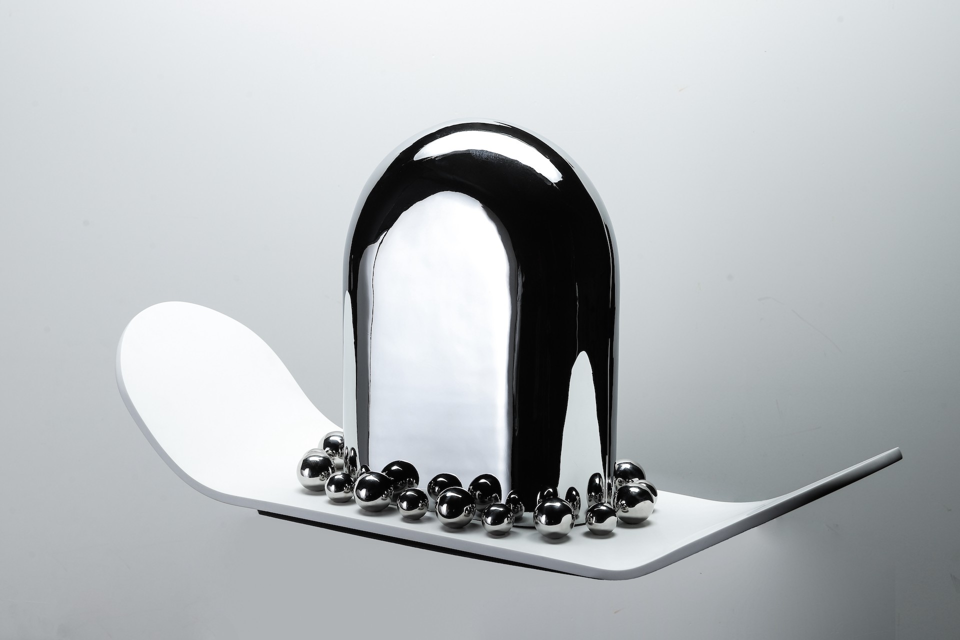 A black and white sculpture with silver balls on top of it.