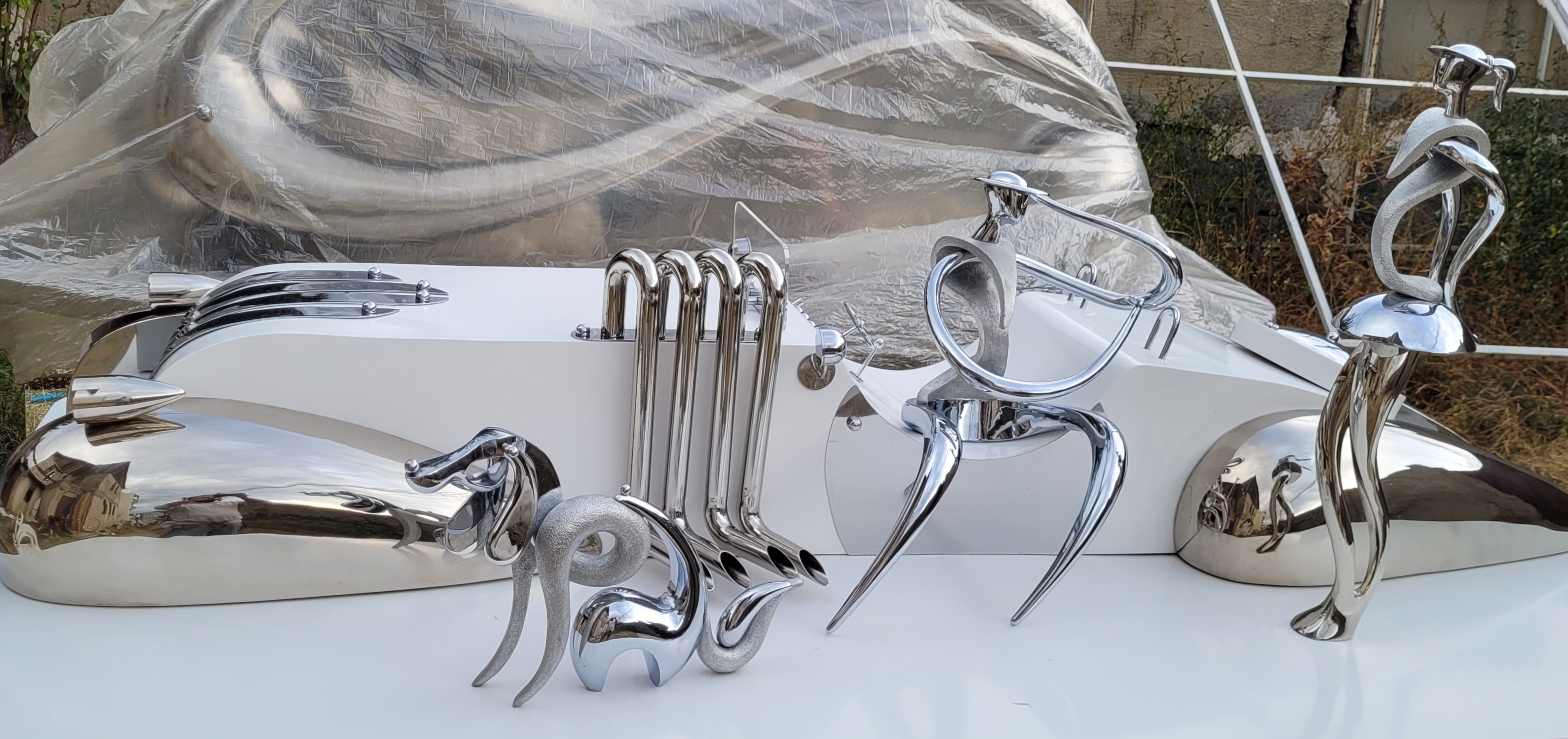 A collection of polished chrome sculptures displayed on a white surface.