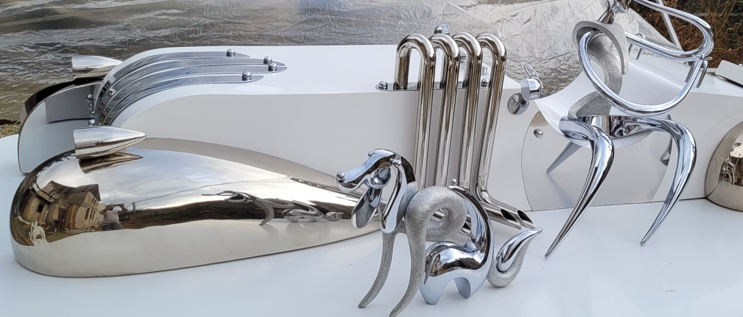 A collection of polished chrome sculptures displayed on a white surface.