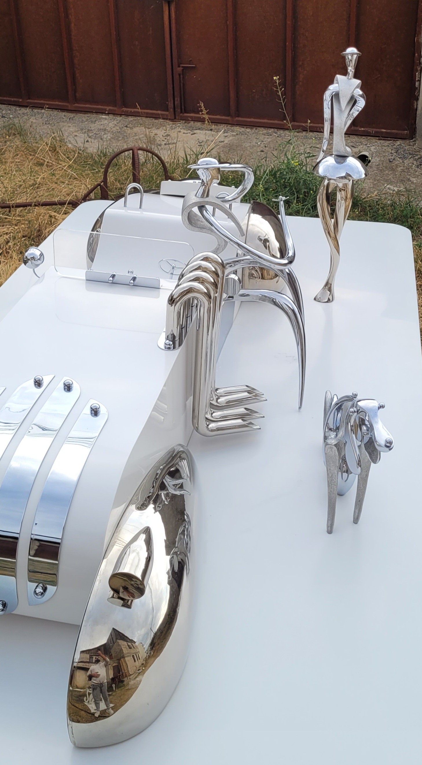 A collection of polished chrome sculptures displayed on a white surface.