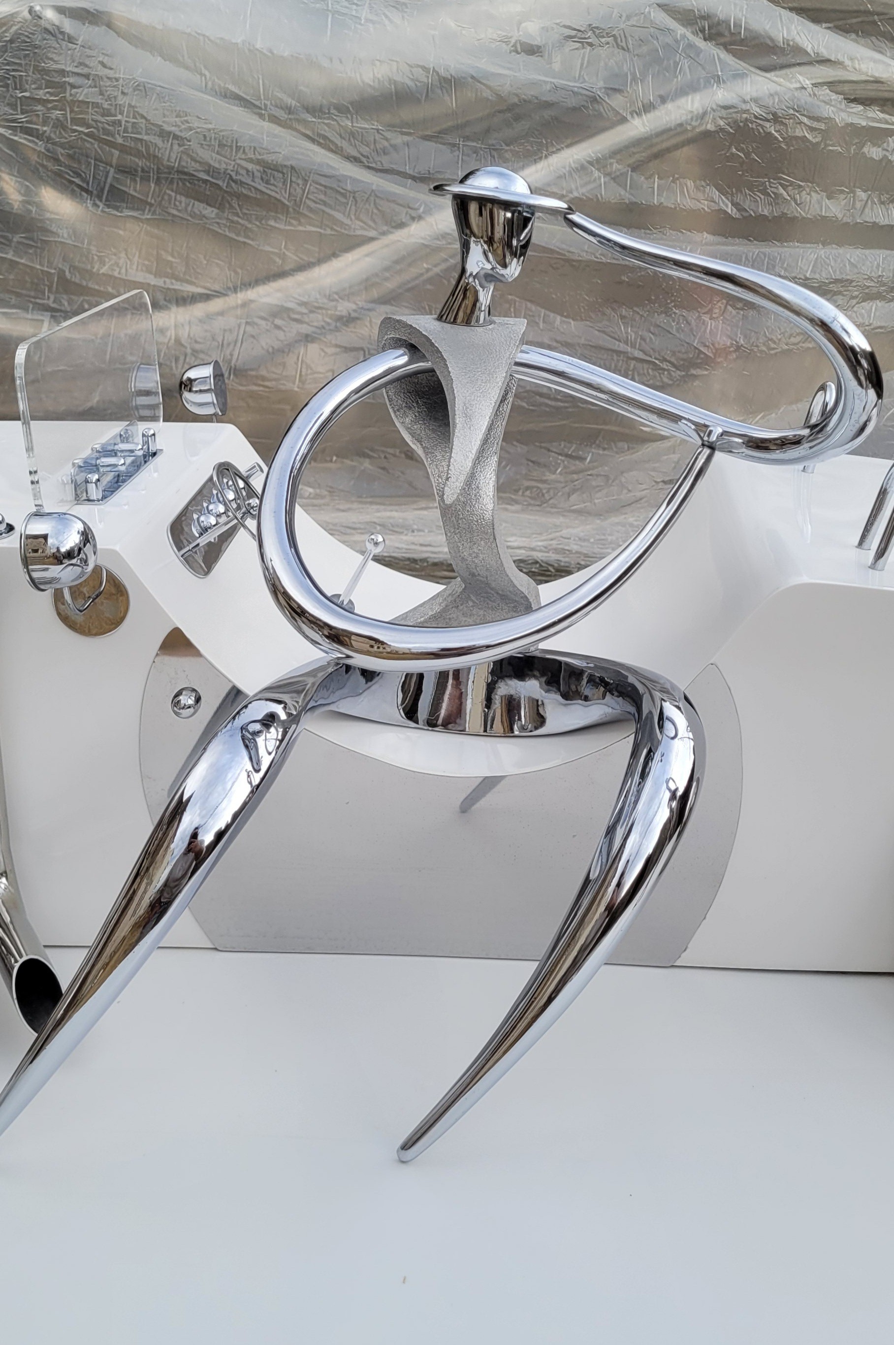 A collection of polished chrome sculptures displayed on a white surface.