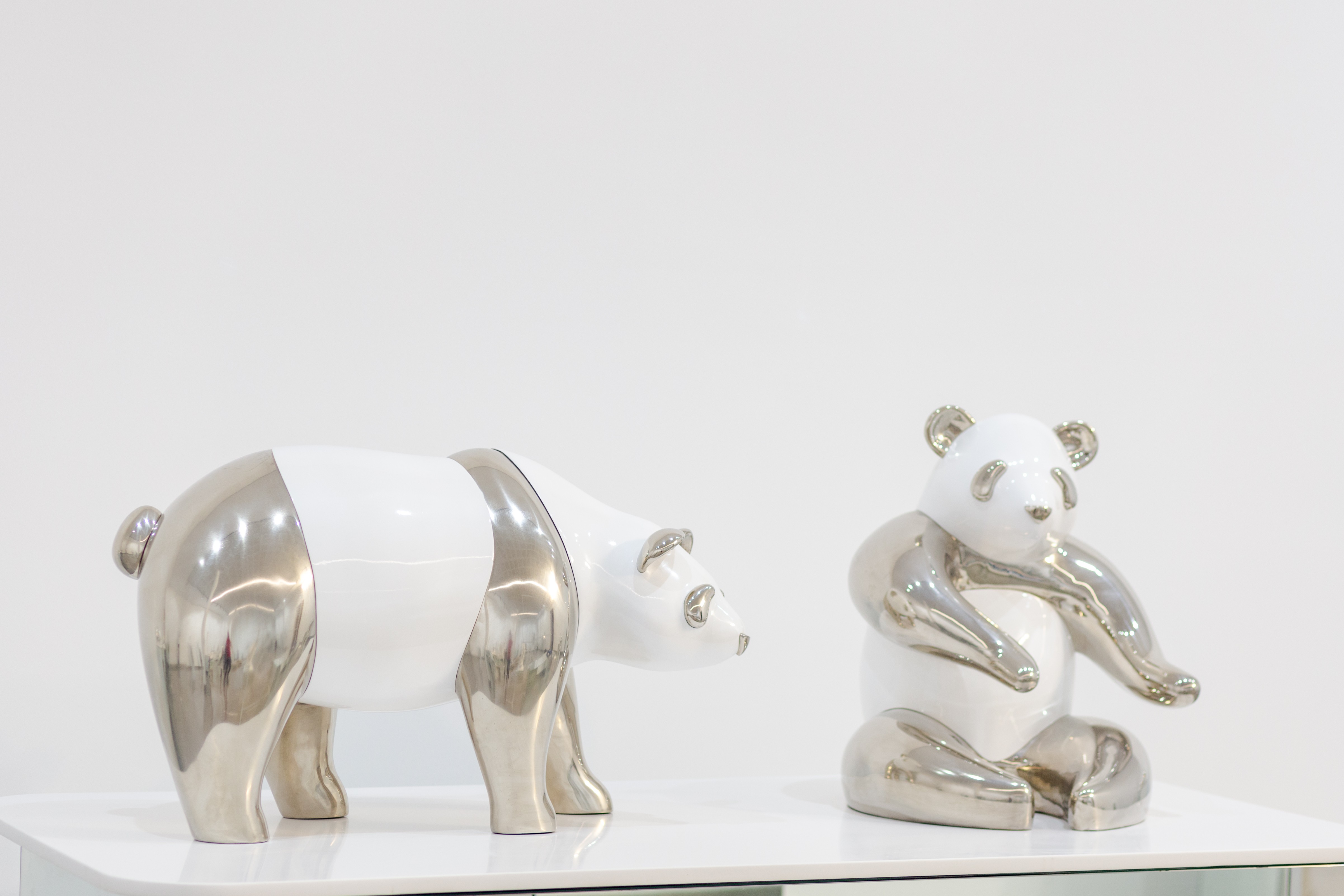 A couple of silver and white bears sitting on top of a table.