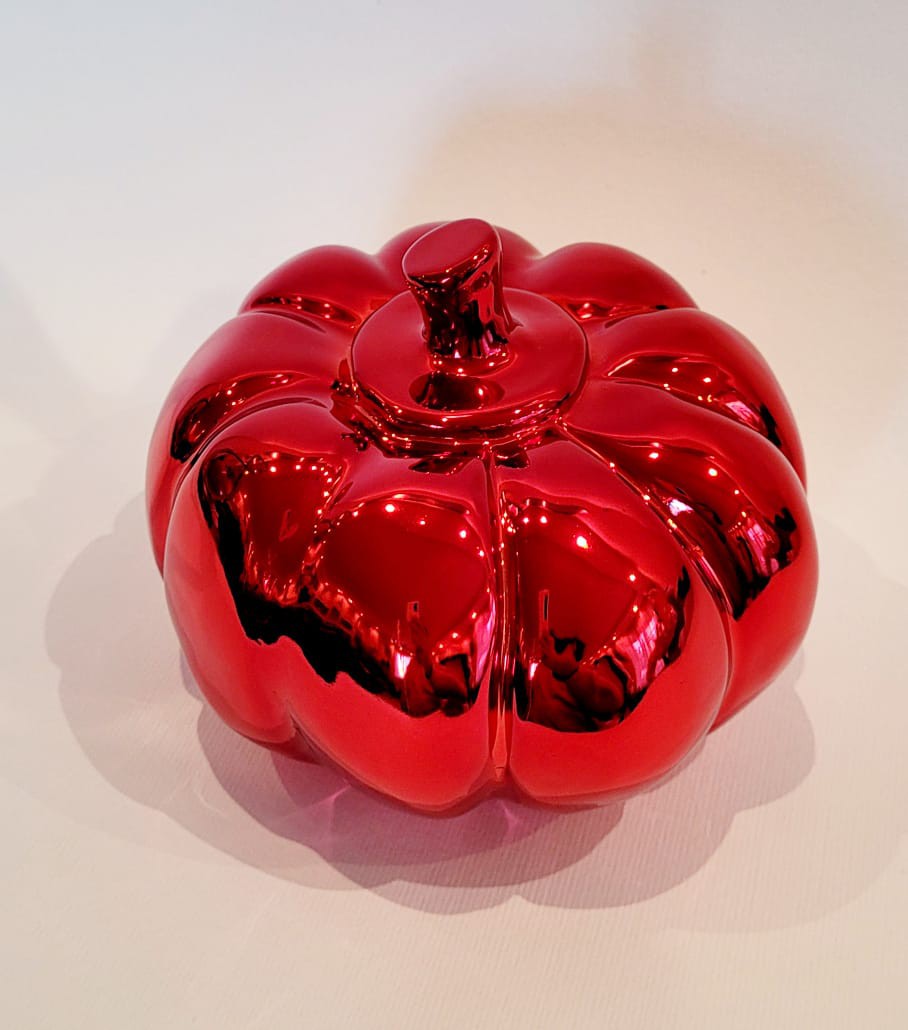 A red glass pumpkin sitting on top of a white surface.