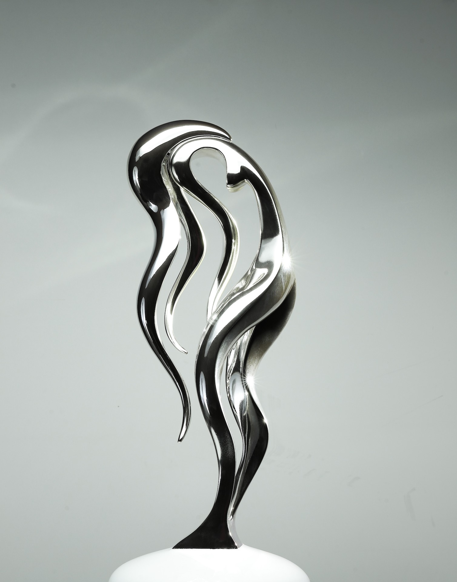 A silver sculpture of a woman's head on a white pedestal.