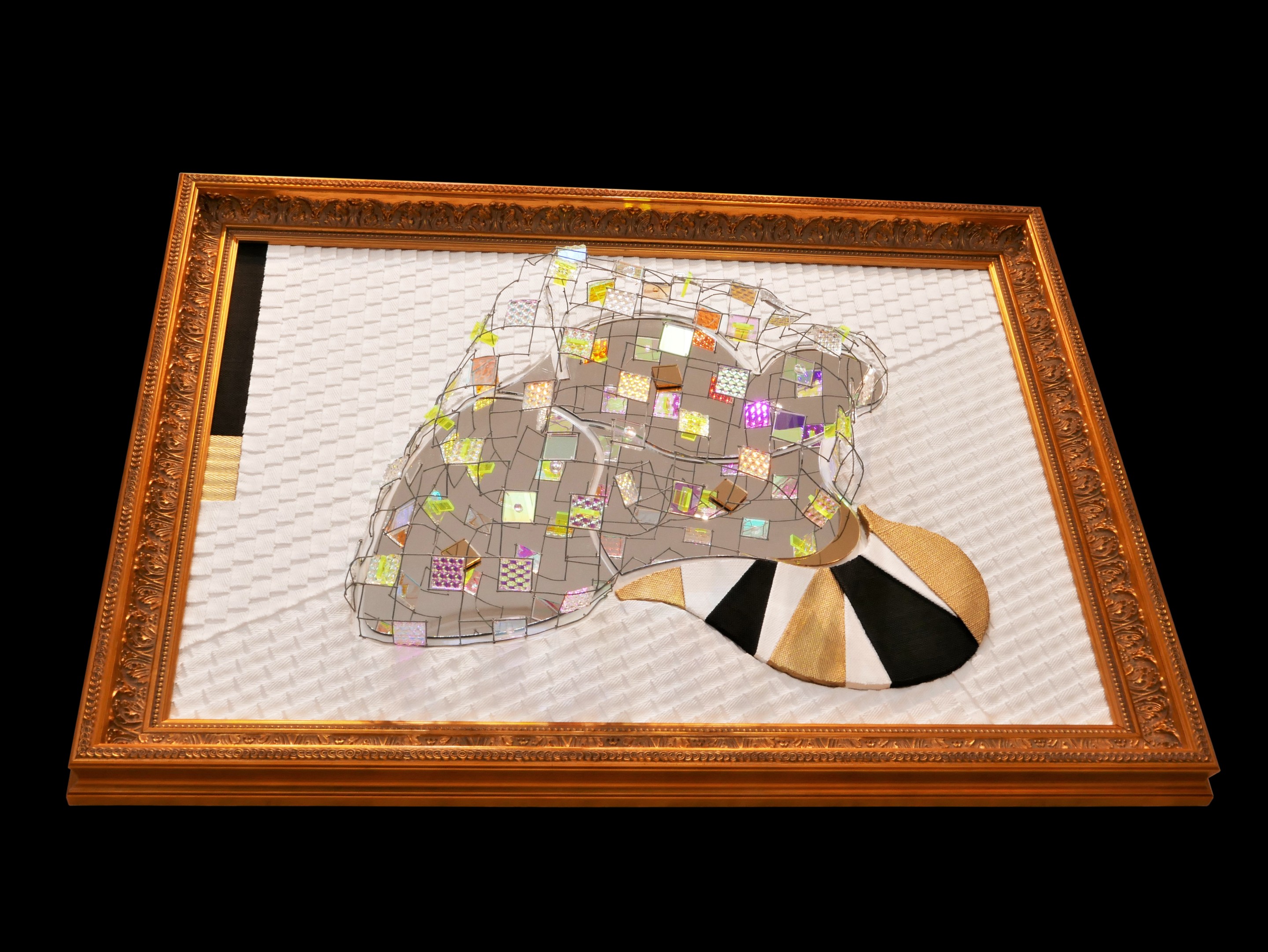 A picture of a mirror sculpture in a gold frame.