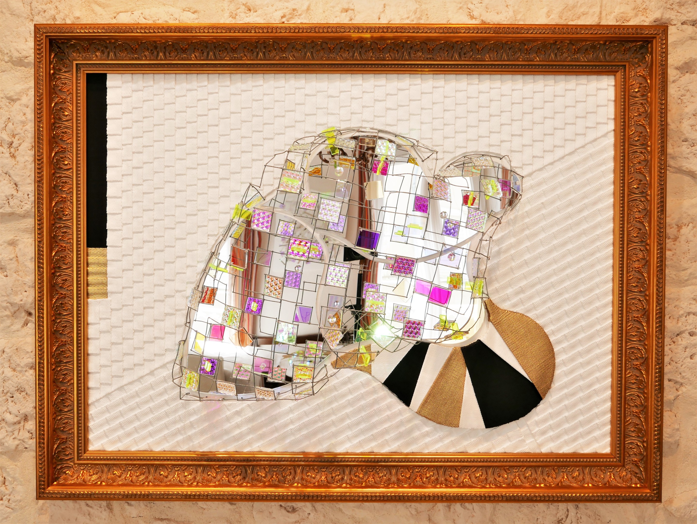 A picture of a mirror sculpture in a gold frame.
