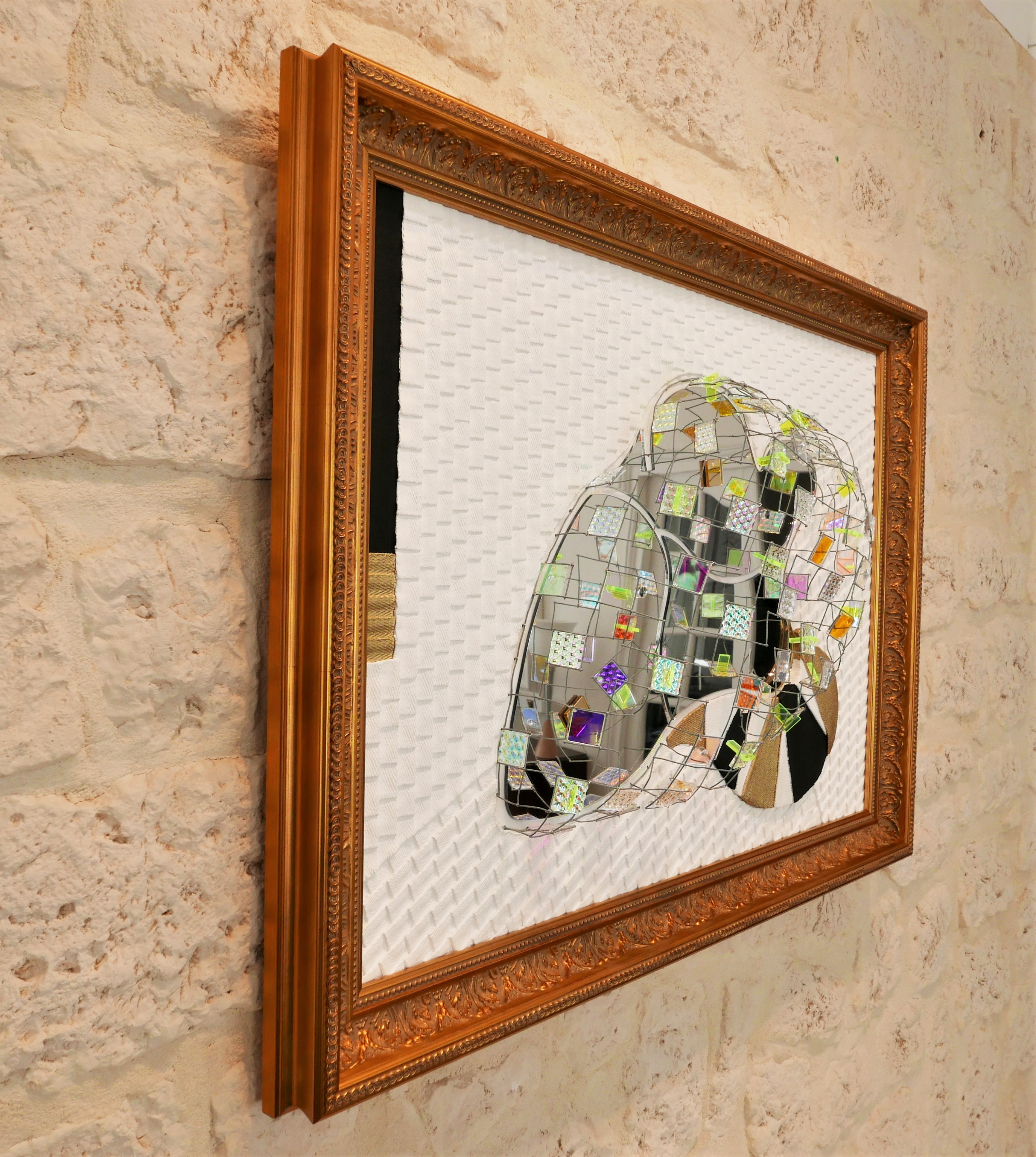 A picture of a mirror sculpture in a gold frame.