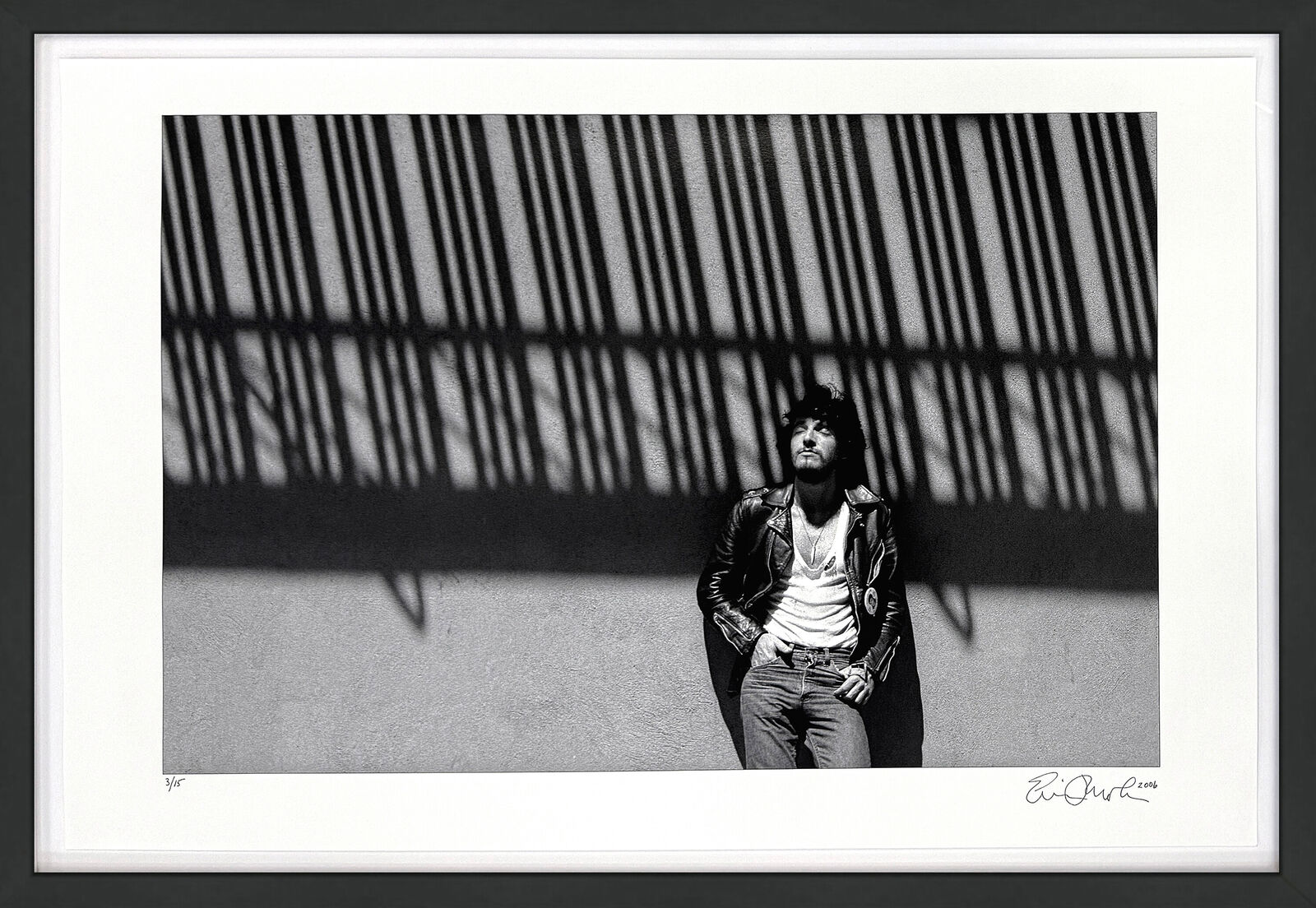 A black and white photo of a man standing in front of a wall.
