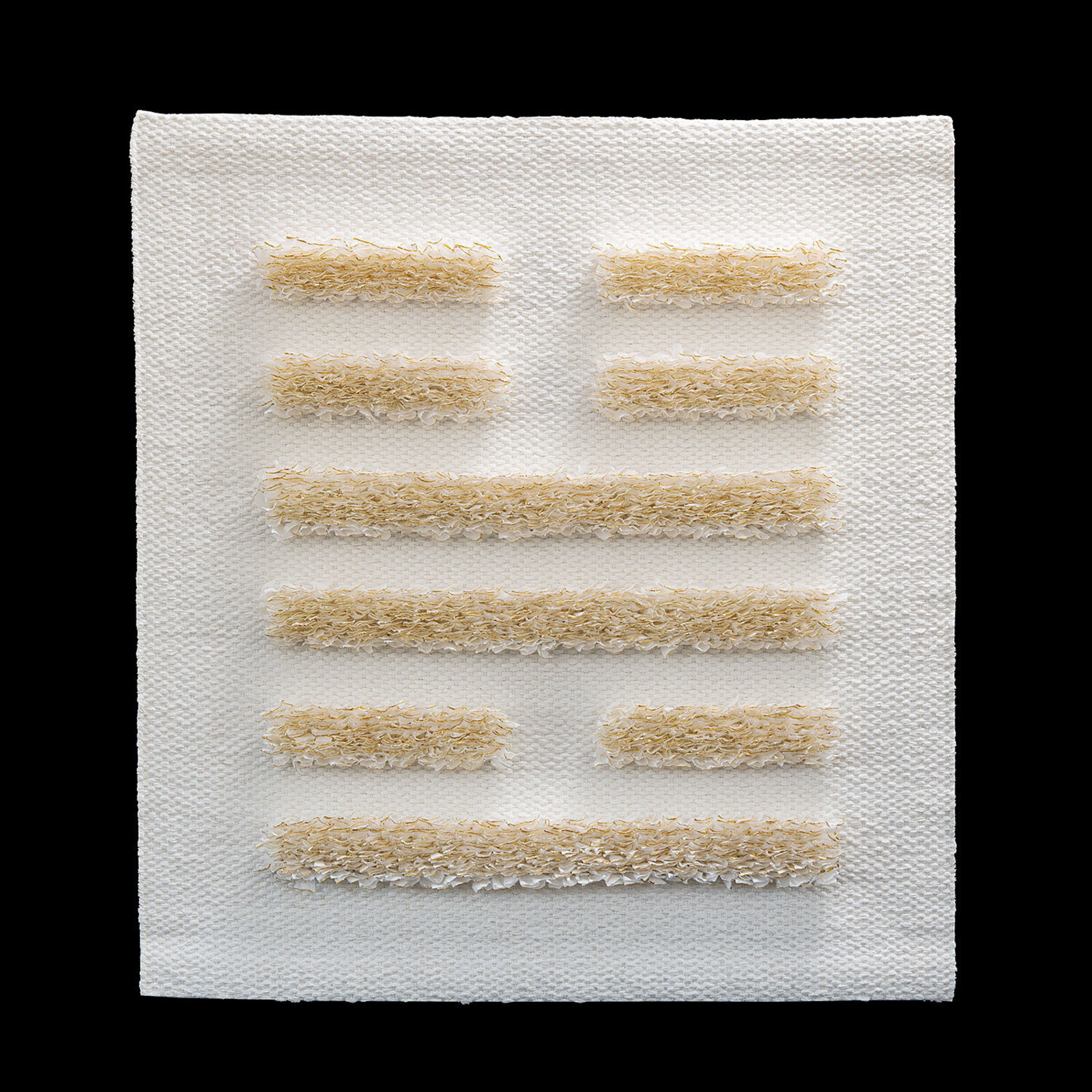 A minimalist textile piece featuring a woven white background with horizontal strips of textured, golden-brown fibers.