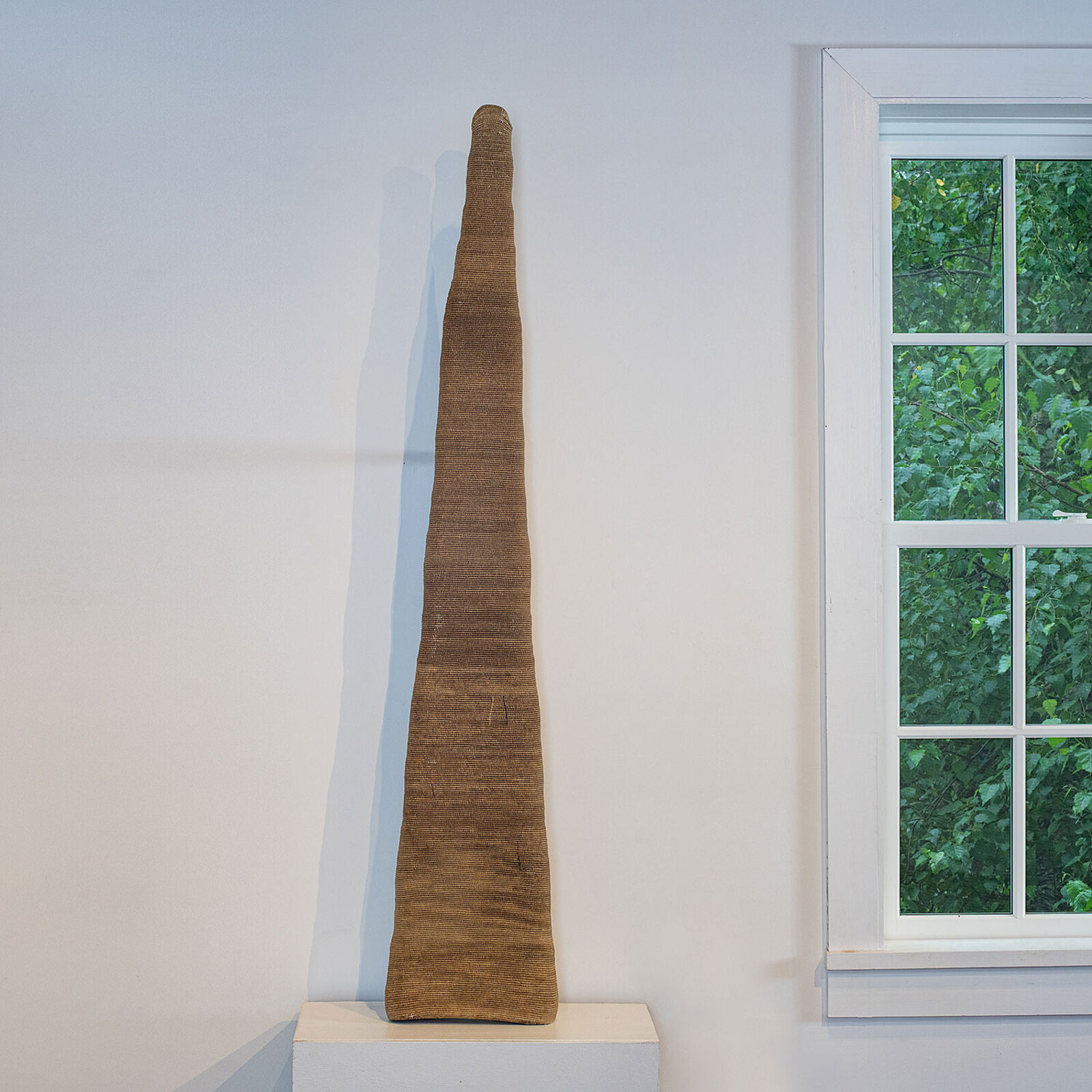 A vase sitting on a shelf next to a window.