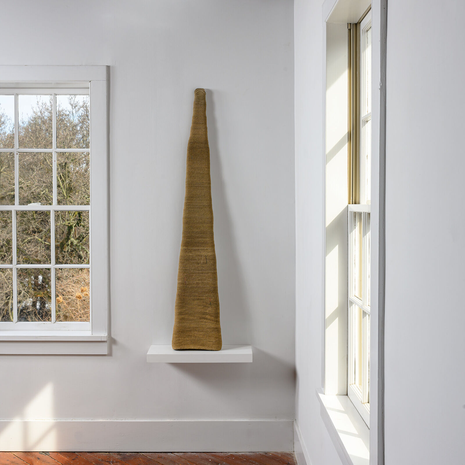 A vase sitting on a shelf next to a window.