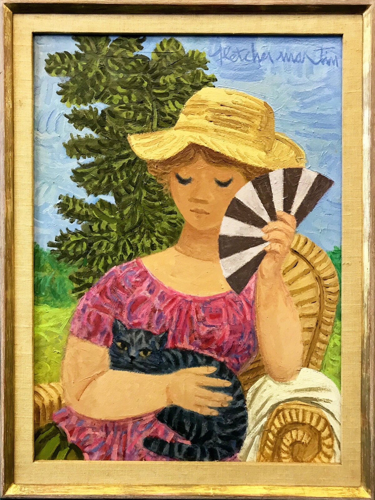 A serene figure in a straw hat holds a fan and cradles a dark cat while seated outdoors.