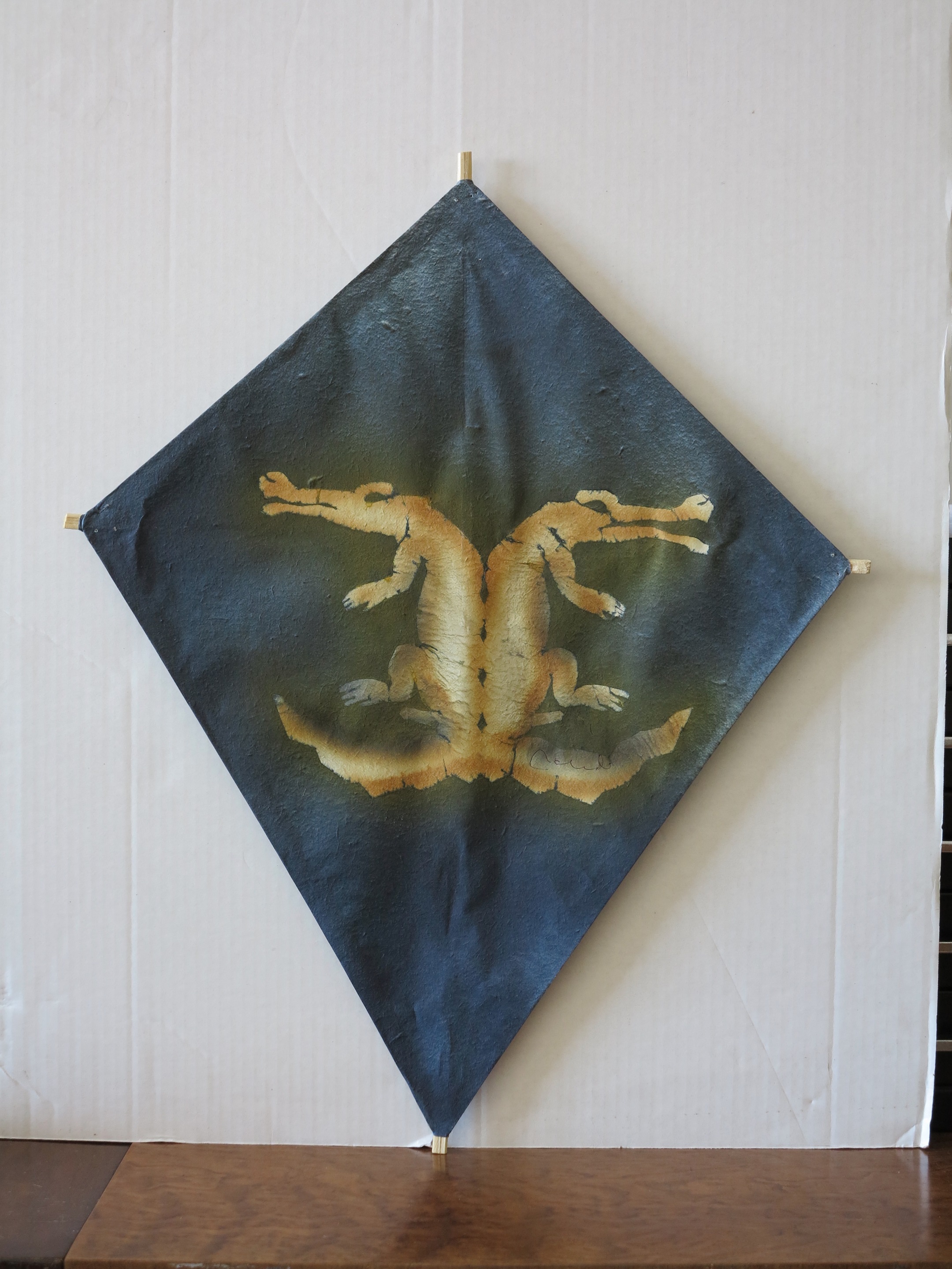A black and gold dragon on a blue and gold kite hanging on a wall.