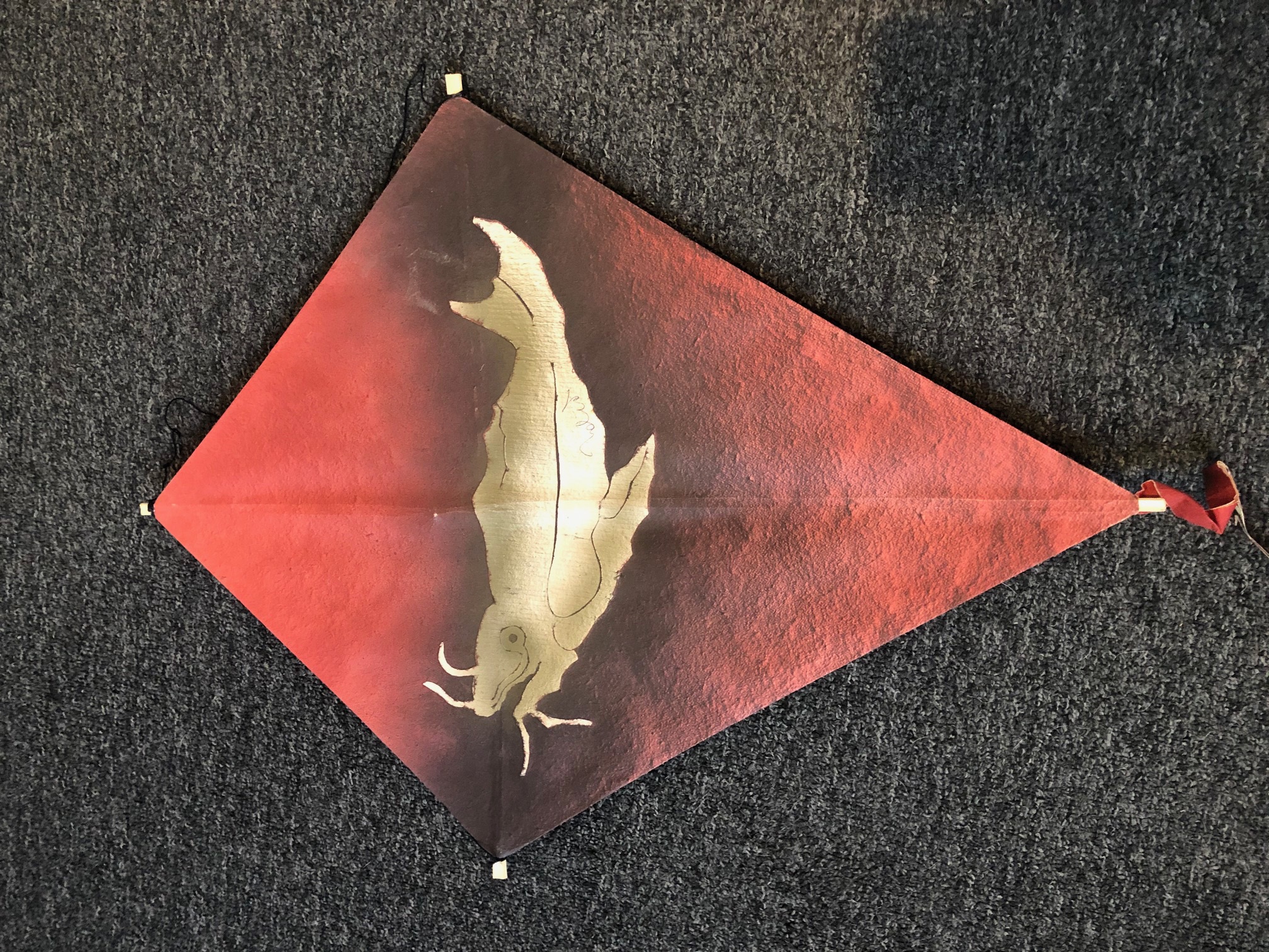 A red kite with a gold fish on it.