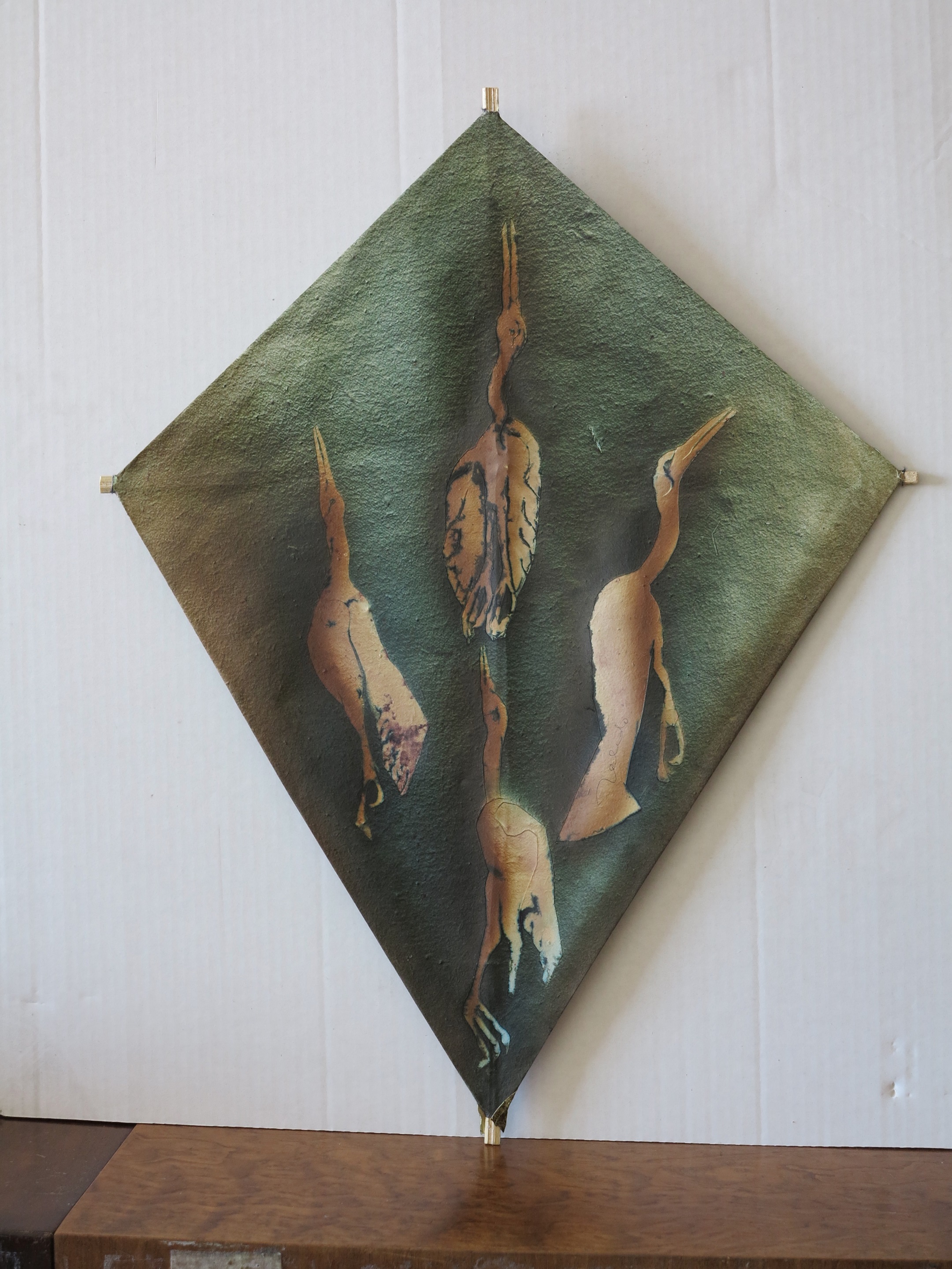 A metal sculpture of three birds on a green background.