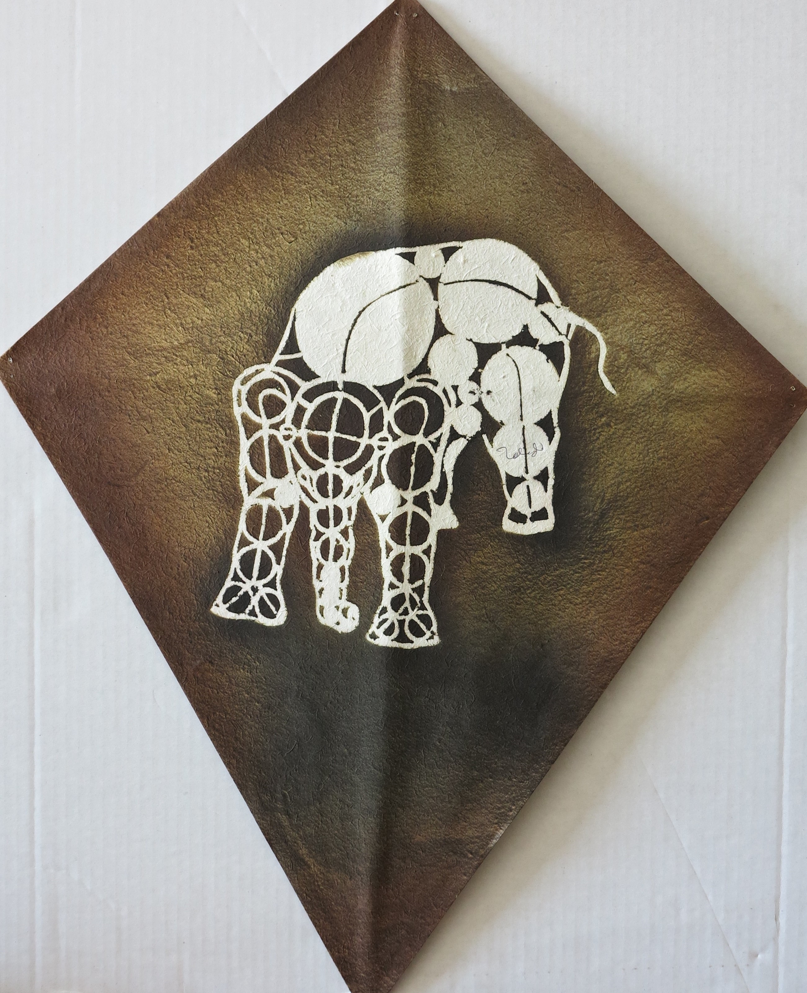 A painting of an elephant on a brown and white wall.