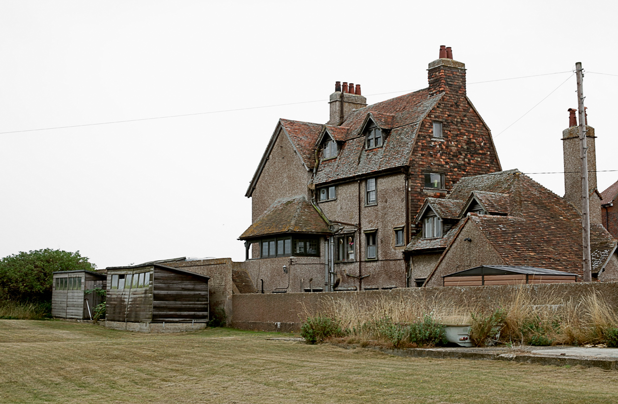 A large brick building with a grassy field in front of it.