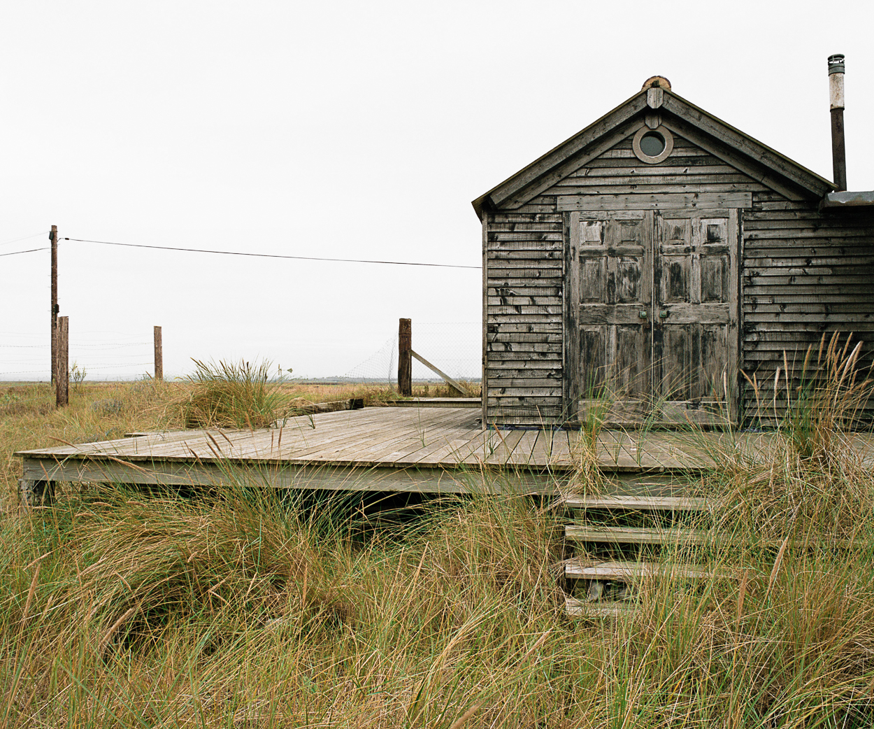 A small wooden building sitting in the middle of a grassy field.