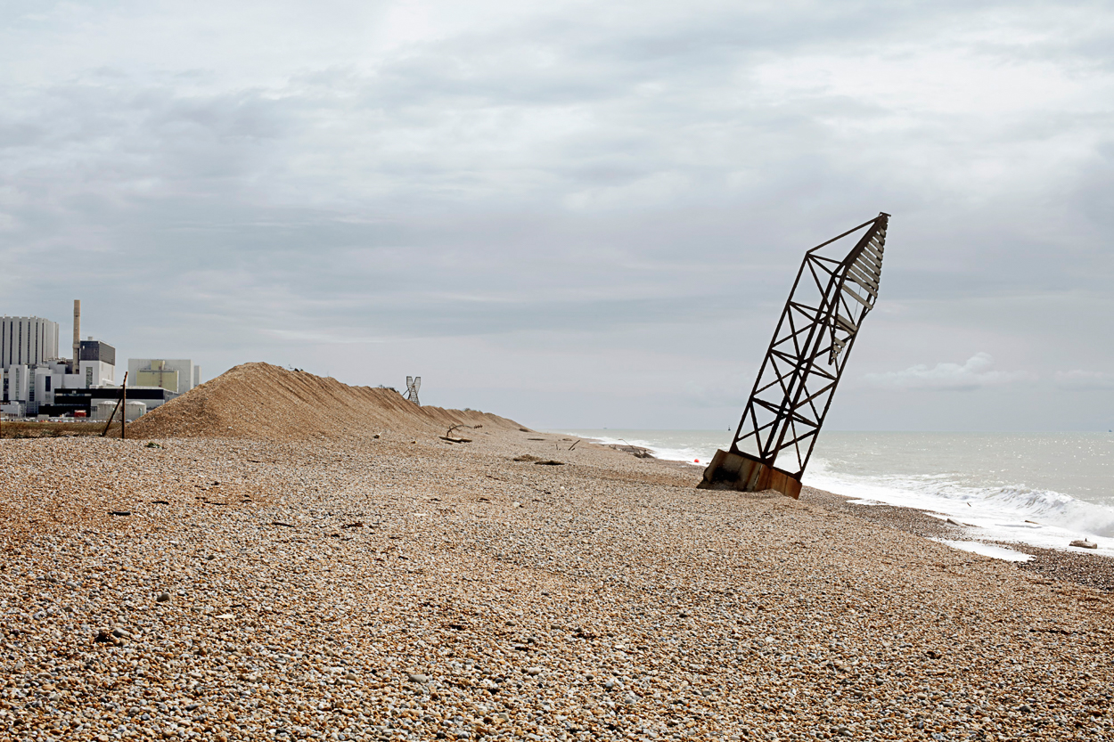 A large metal structure sitting on top of a beach next to the ocean.