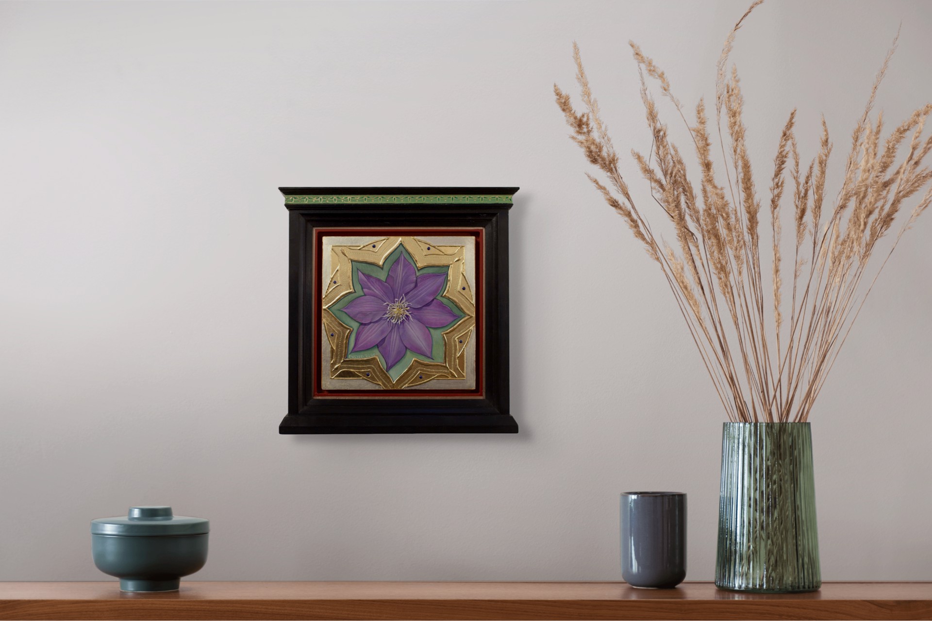 A purple flower set within an ornate gold frame on a red background.