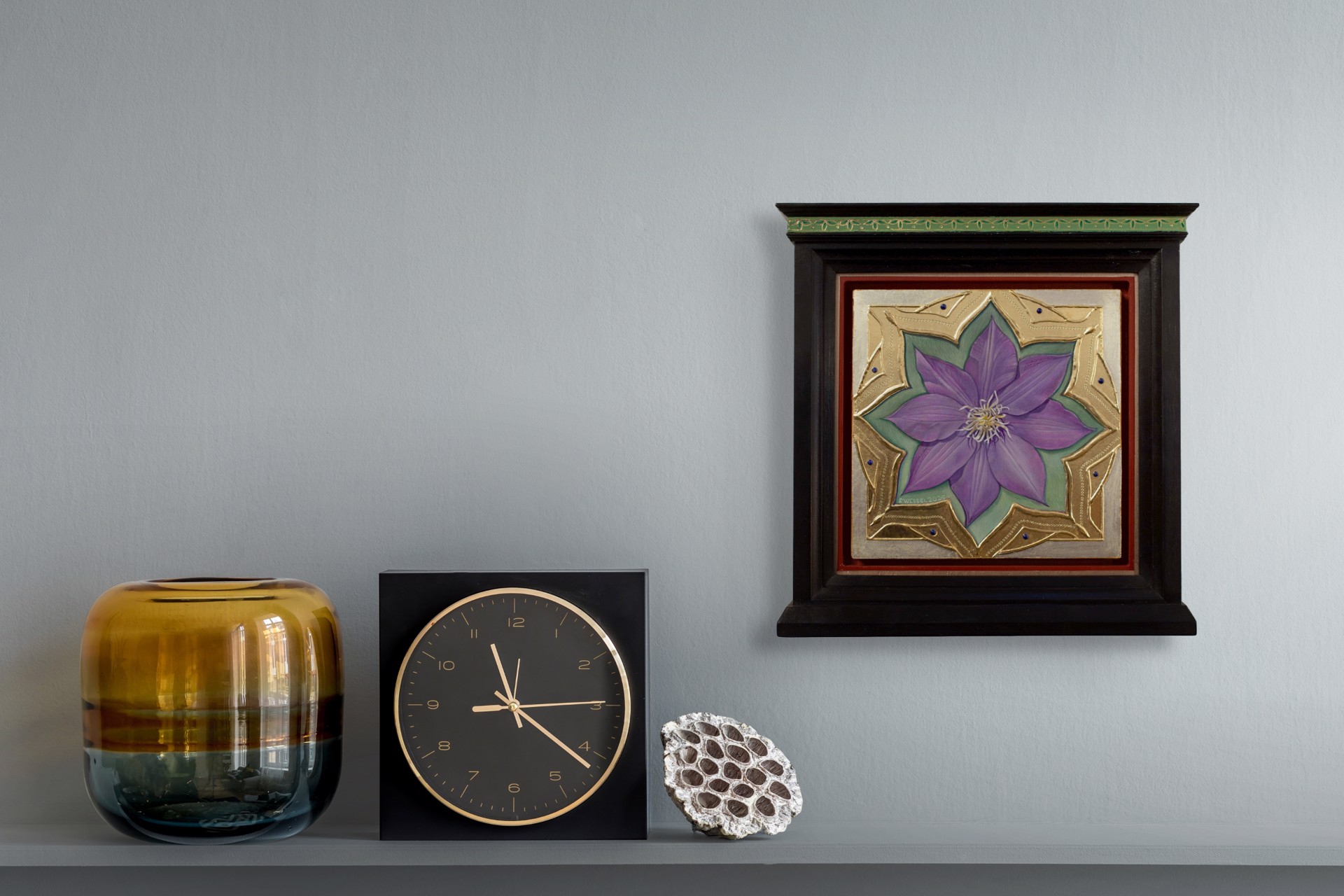A purple flower set within an ornate gold frame on a red background.