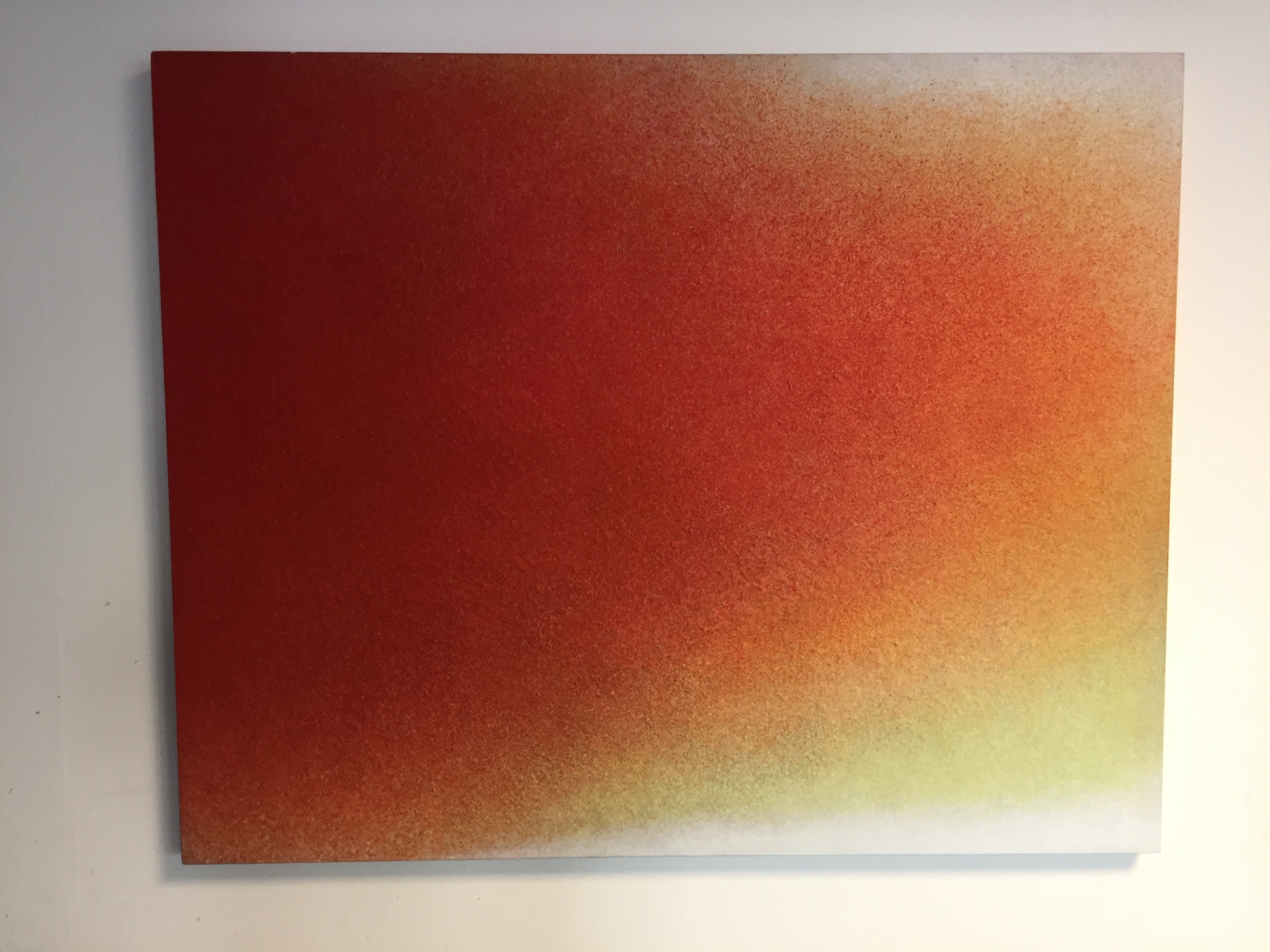 A painting on a white wall with a red and yellow background.