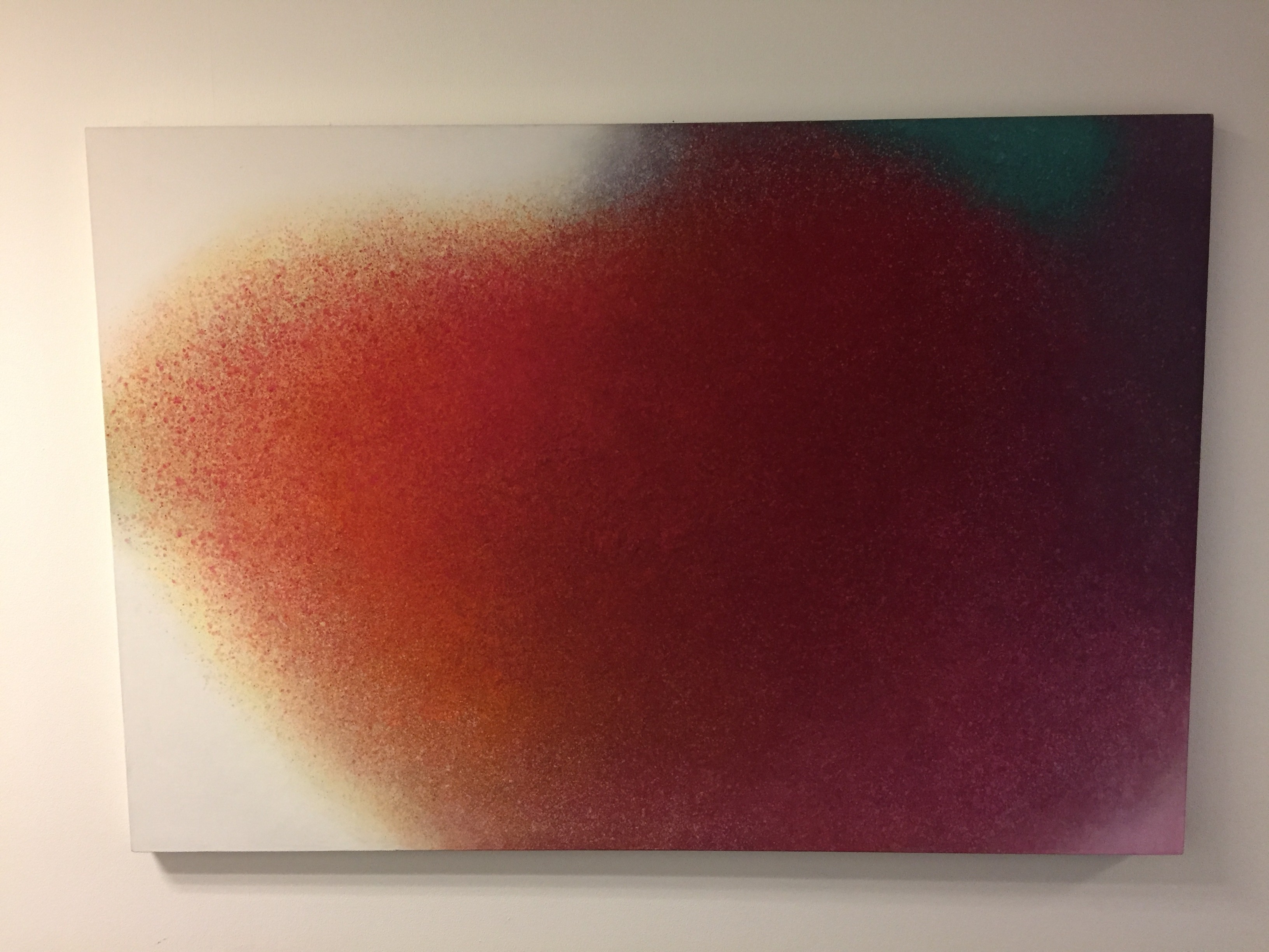A painting on a white wall with a red and green background.