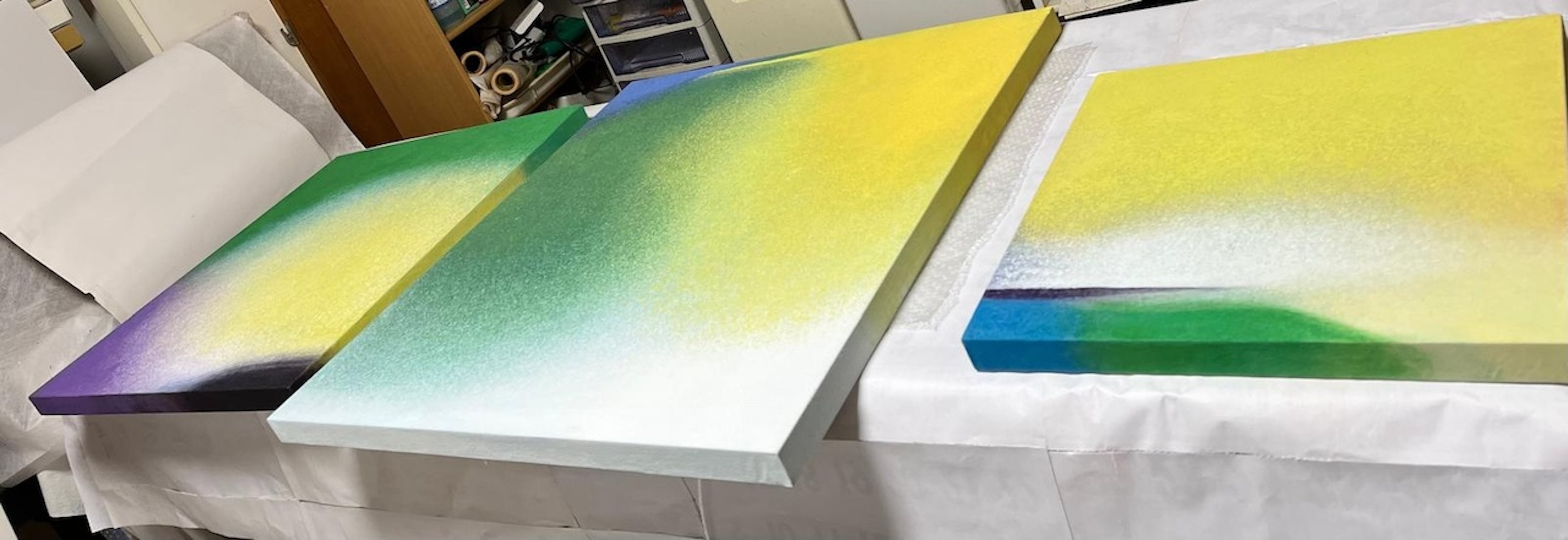 An abstract composition featuring a textured gradient from yellow to white, resting on a dark horizon line with hints of blue and green.