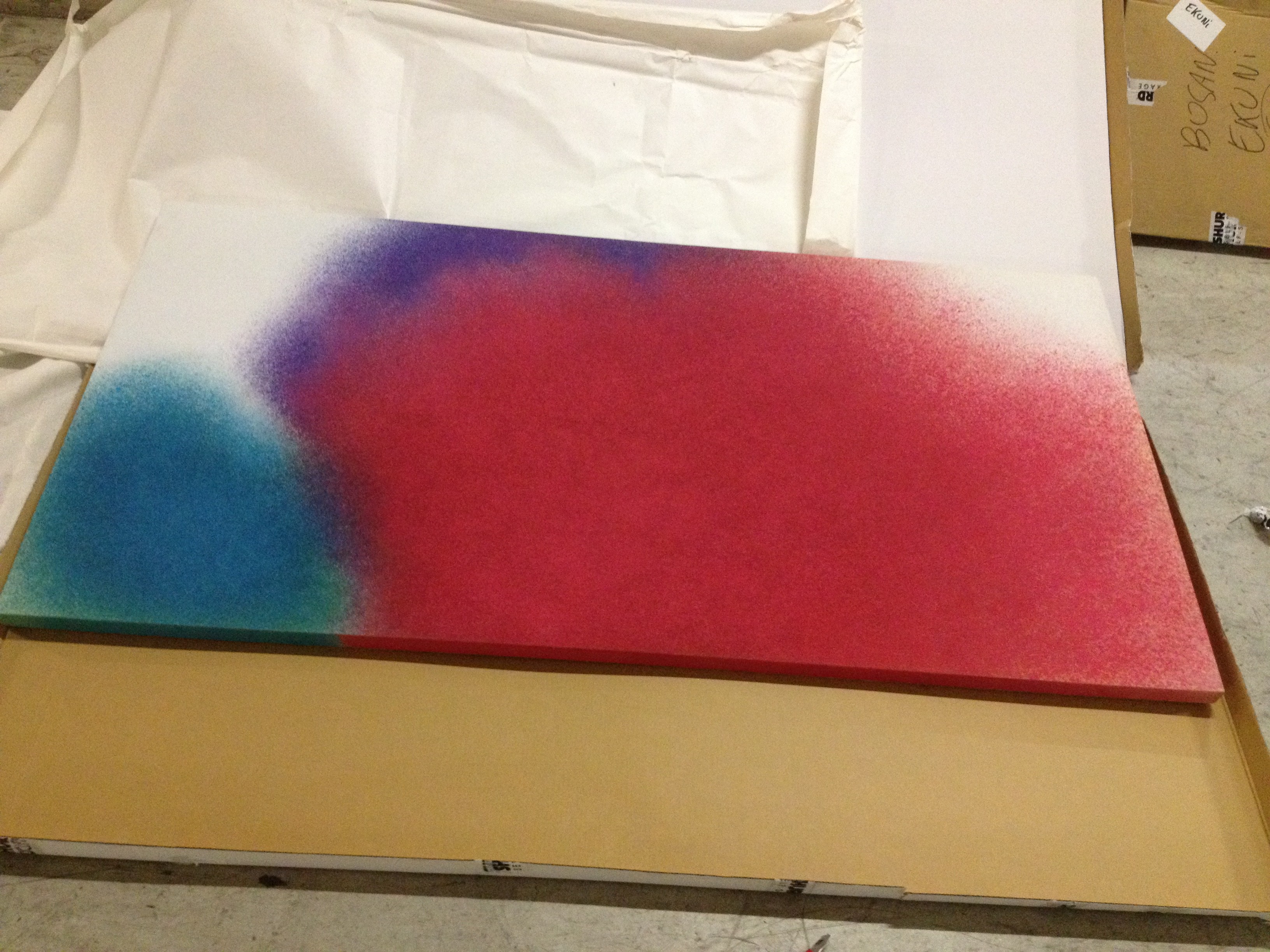 A minimalist abstract piece featuring a large red shape with blue and purple accents on a white background.