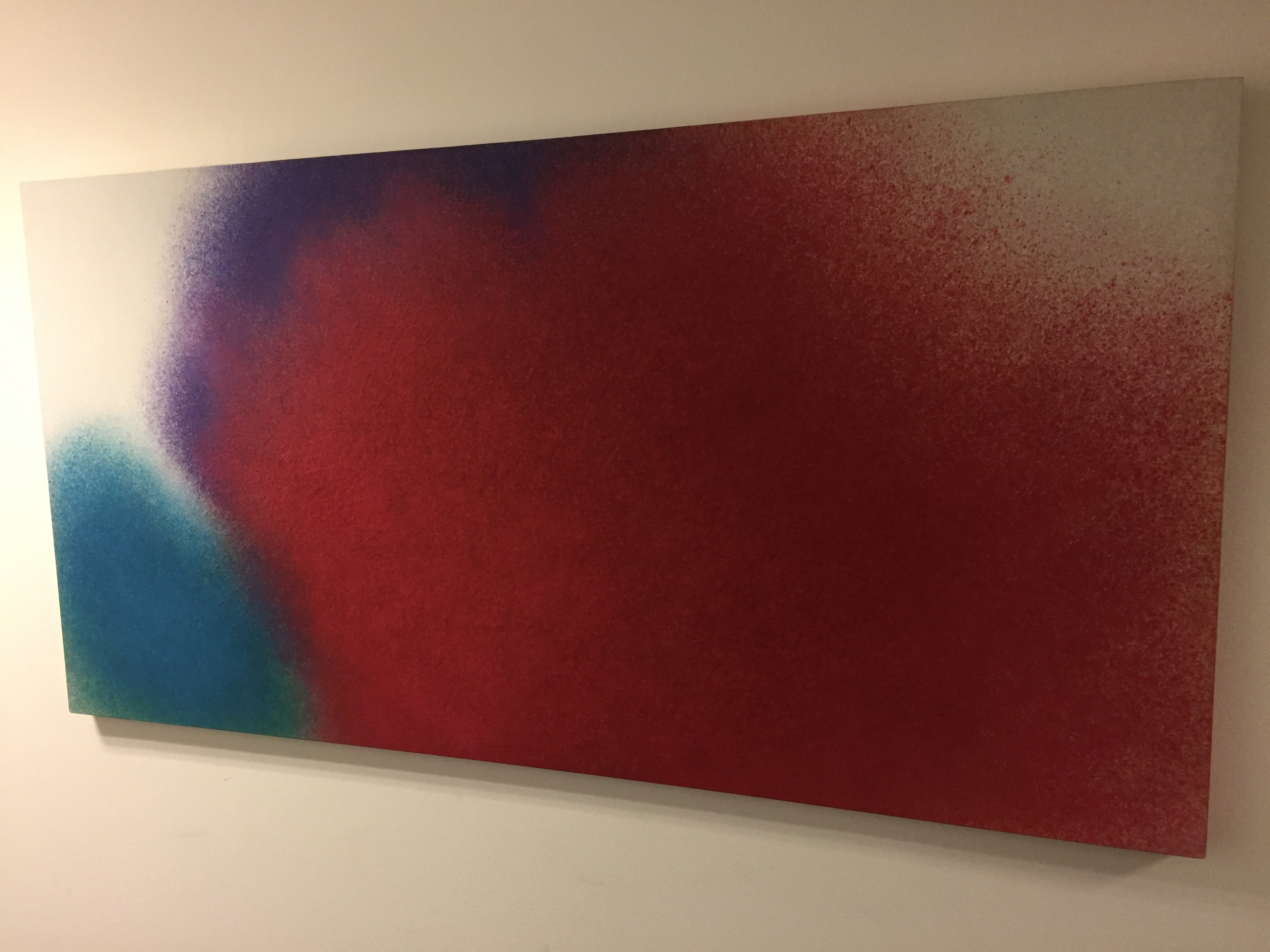 A minimalist abstract piece featuring a large red shape with blue and purple accents on a white background.