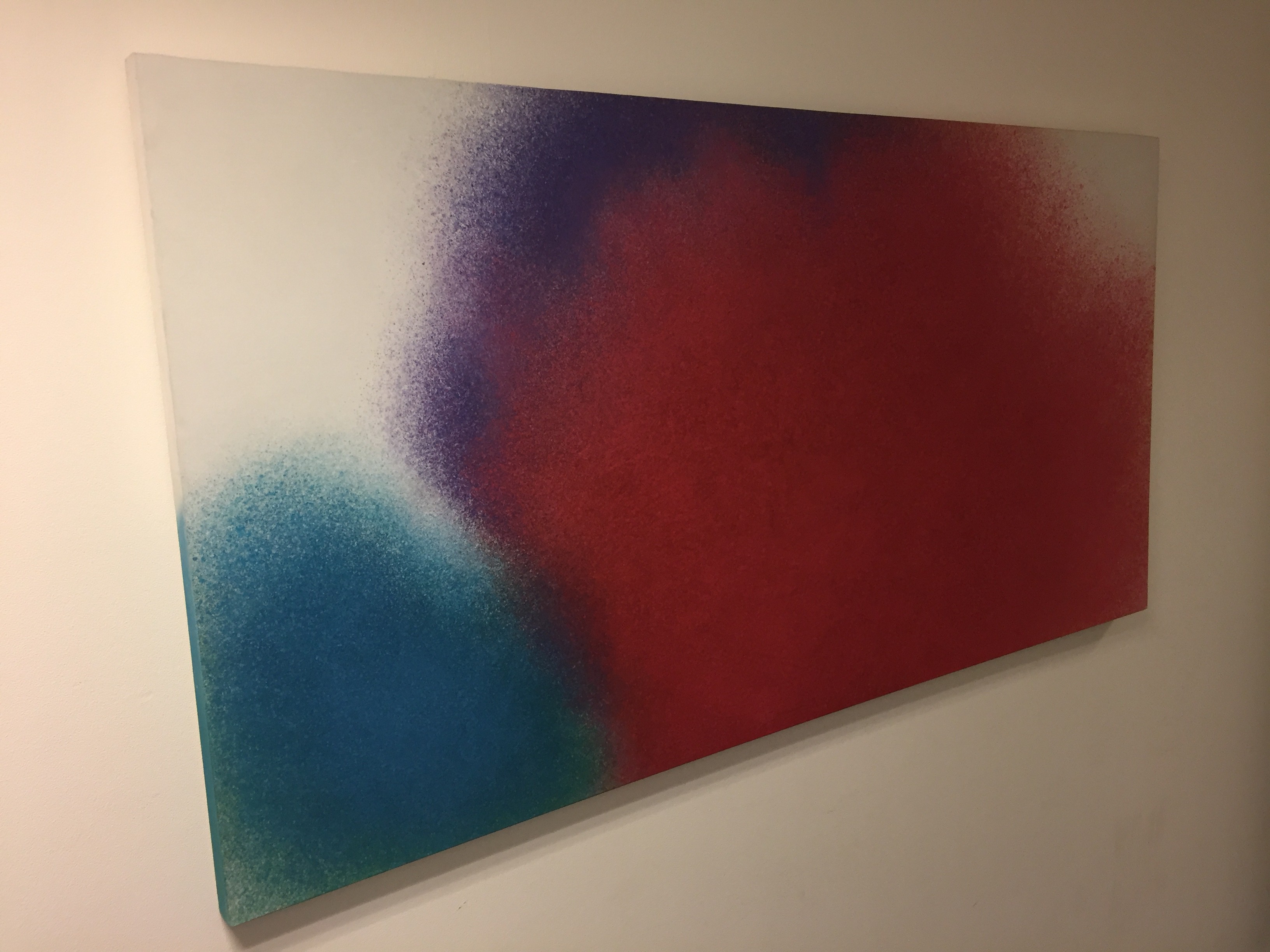 A minimalist abstract piece featuring a large red shape with blue and purple accents on a white background.