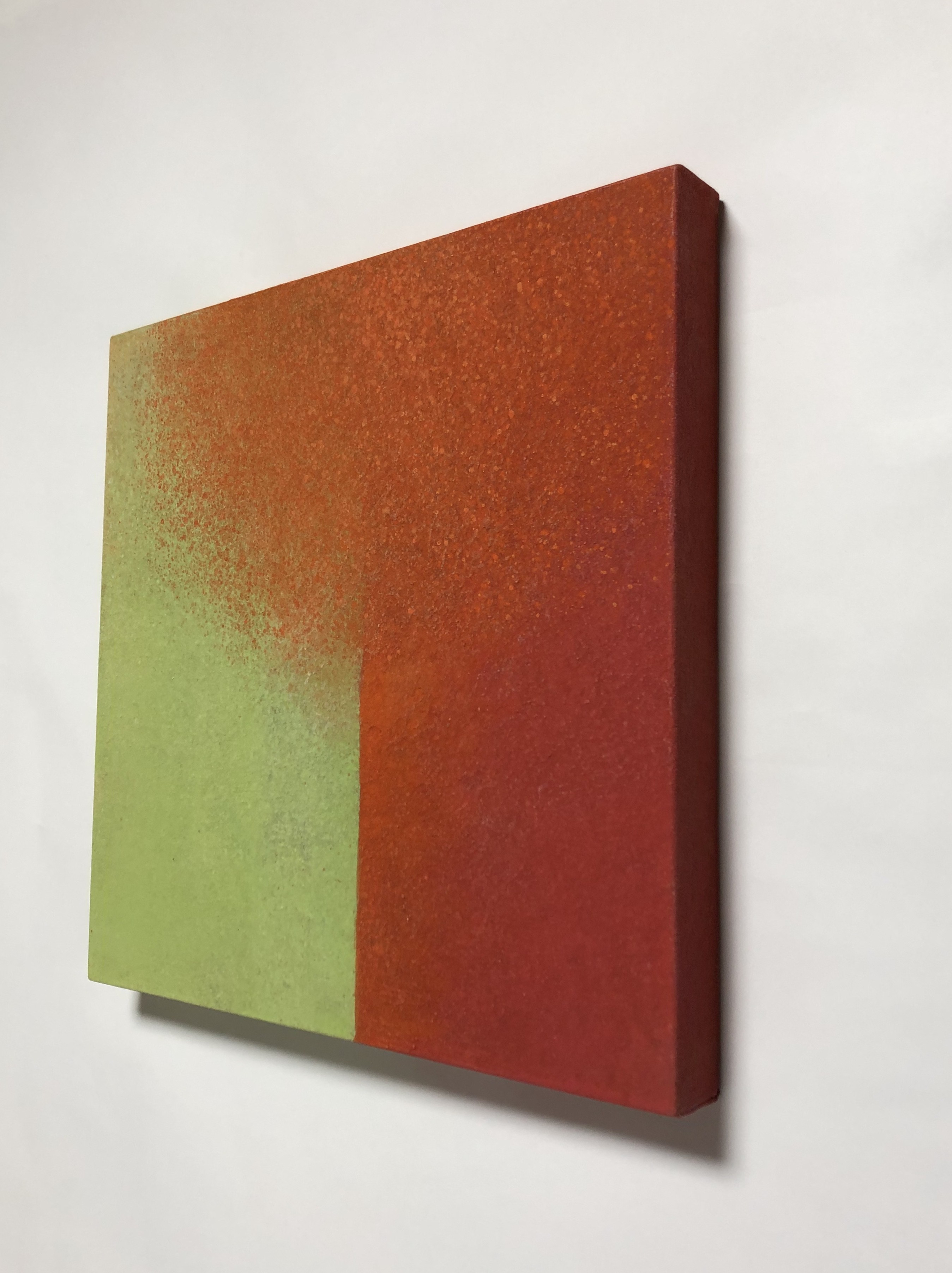 A painting on a white wall with a red and green color block.